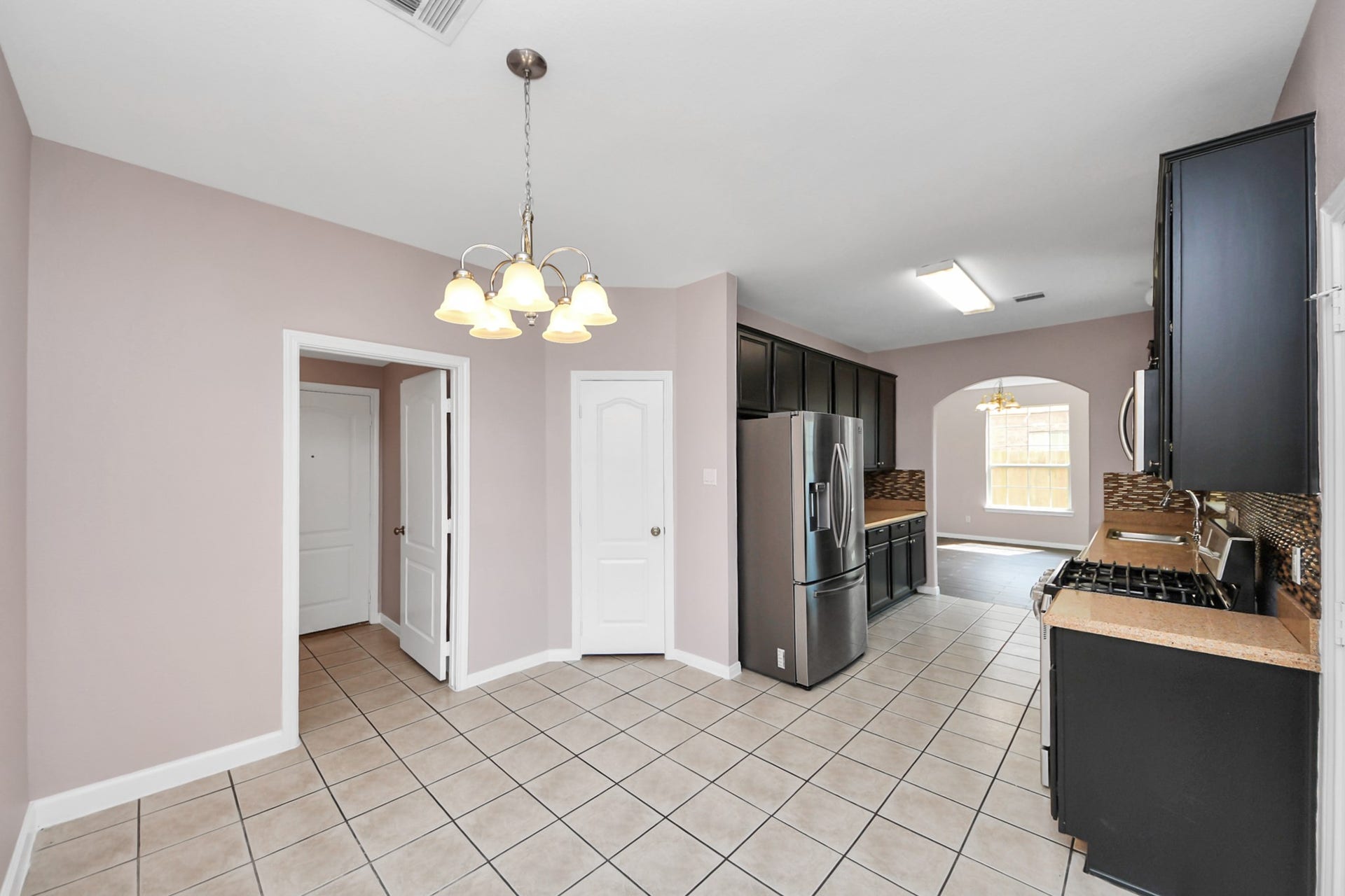 10026 Gil Jr Lane, Houston, TX 77075 Bright kitchen with modern appliances, sleek dark cabinetry, and a cozy dining area under a stylish light fixture.