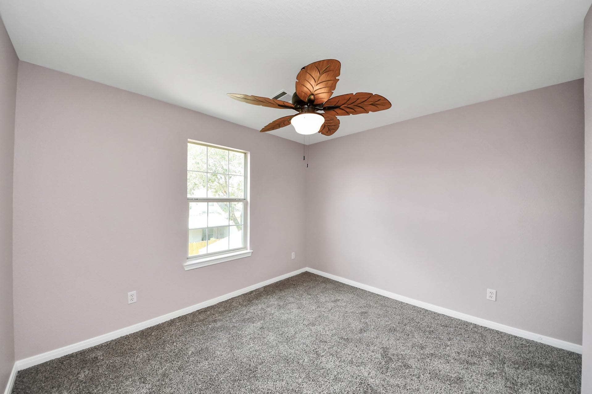 10026 Gil Jr Lane, Houston, TX 77075 Discover the charm of Bedroom 4, featuring soft pastel walls and plush carpeting, illuminated by natural light from a large window and a stylish ceiling fan.