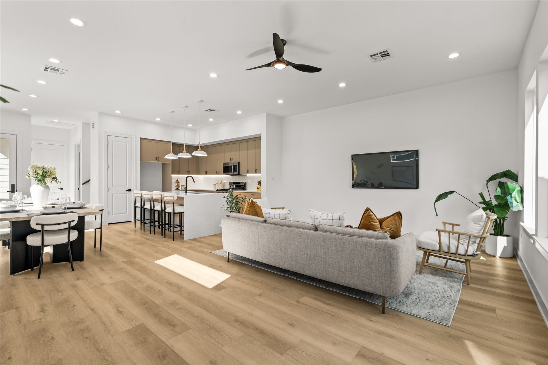 This view shows the depth and open layout of the main floor. The LVP flooring runs continuously from the living room windows, past the kitchen island, and right into the dining area, making the entire space easy to navigate and use.