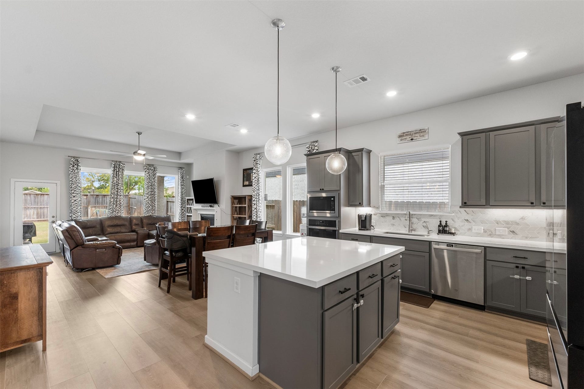 22107 Palo Dura Lane, Tomball, TX 77375 Spacious open-concept kitchen and living area featuring a large island with modern pendant lighting, sleek gray cabinetry, and stainless steel appliances.