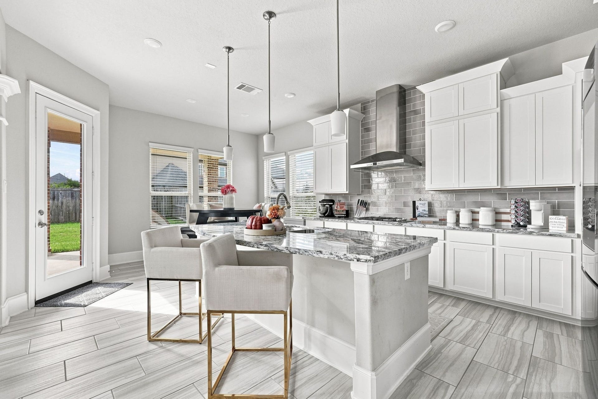 30719 Barred Owl Way, Fulshear, TX 77423 A beautifully appointed kitchen showcases crisp white cabinetry, gorgeous granite countertops, and a designer tile backsplash.