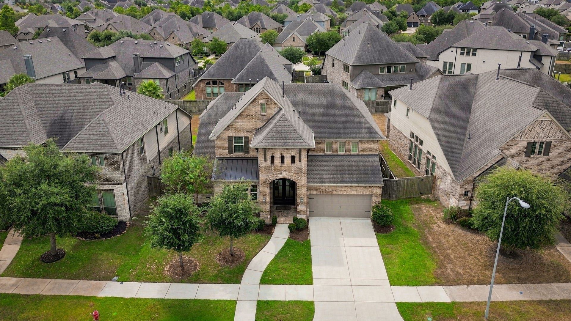 30719 Barred Owl Way, Fulshear, TX 77423 A beautiful aerial perspective showcases the homes impressive two-story architecture and stately brick exterior.