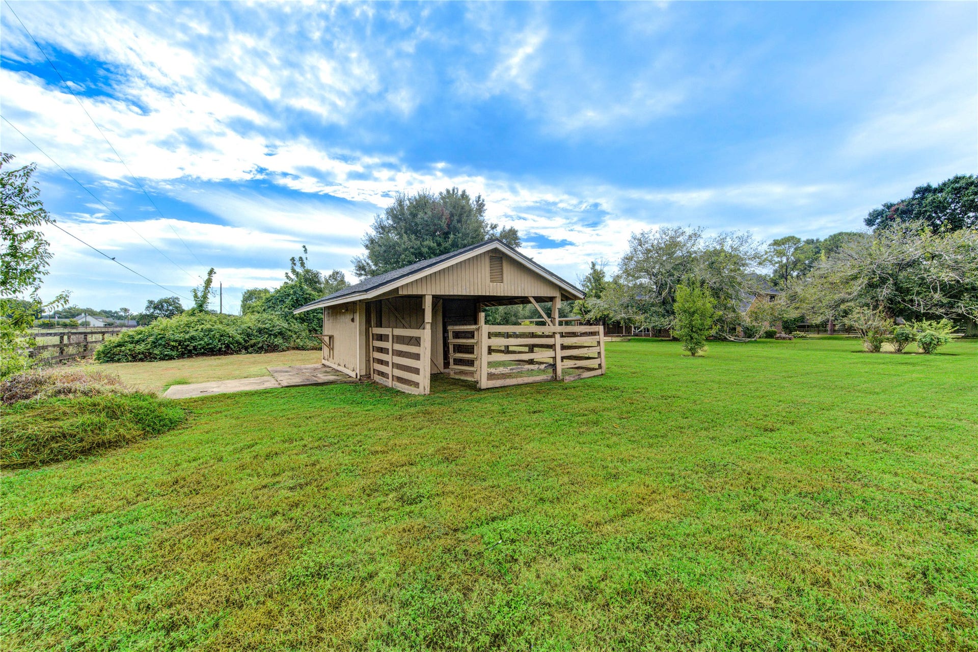 Charming rustic barn nestled in a sprawling, lush green yard, perfect for those seeking tranquility and ample outdoor space.