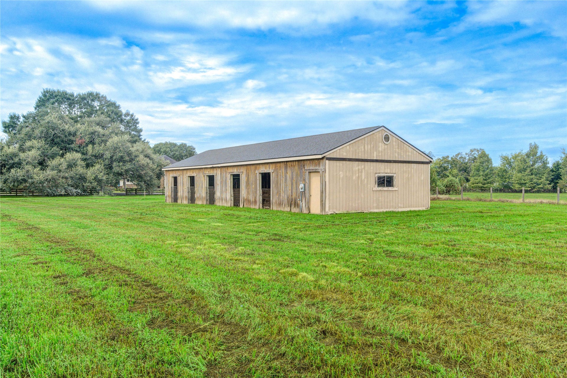 Spacious barn set in a lush, green pasture, perfect for equestrian or agricultural use, surrounded by serene countryside.