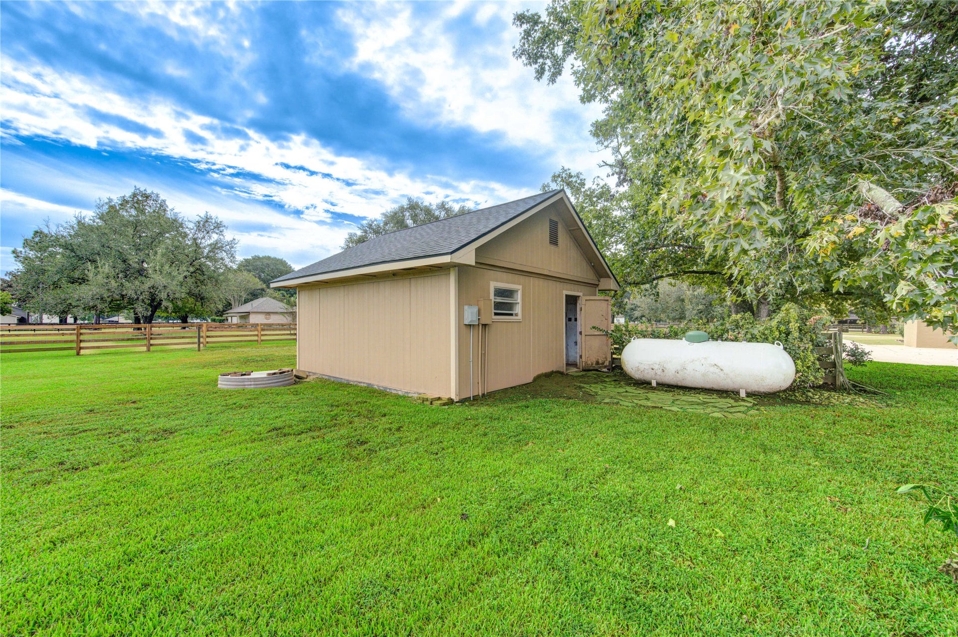 Charming storage shed set amidst a spacious, lush green yard, perfect for outdoor activities and storage needs.