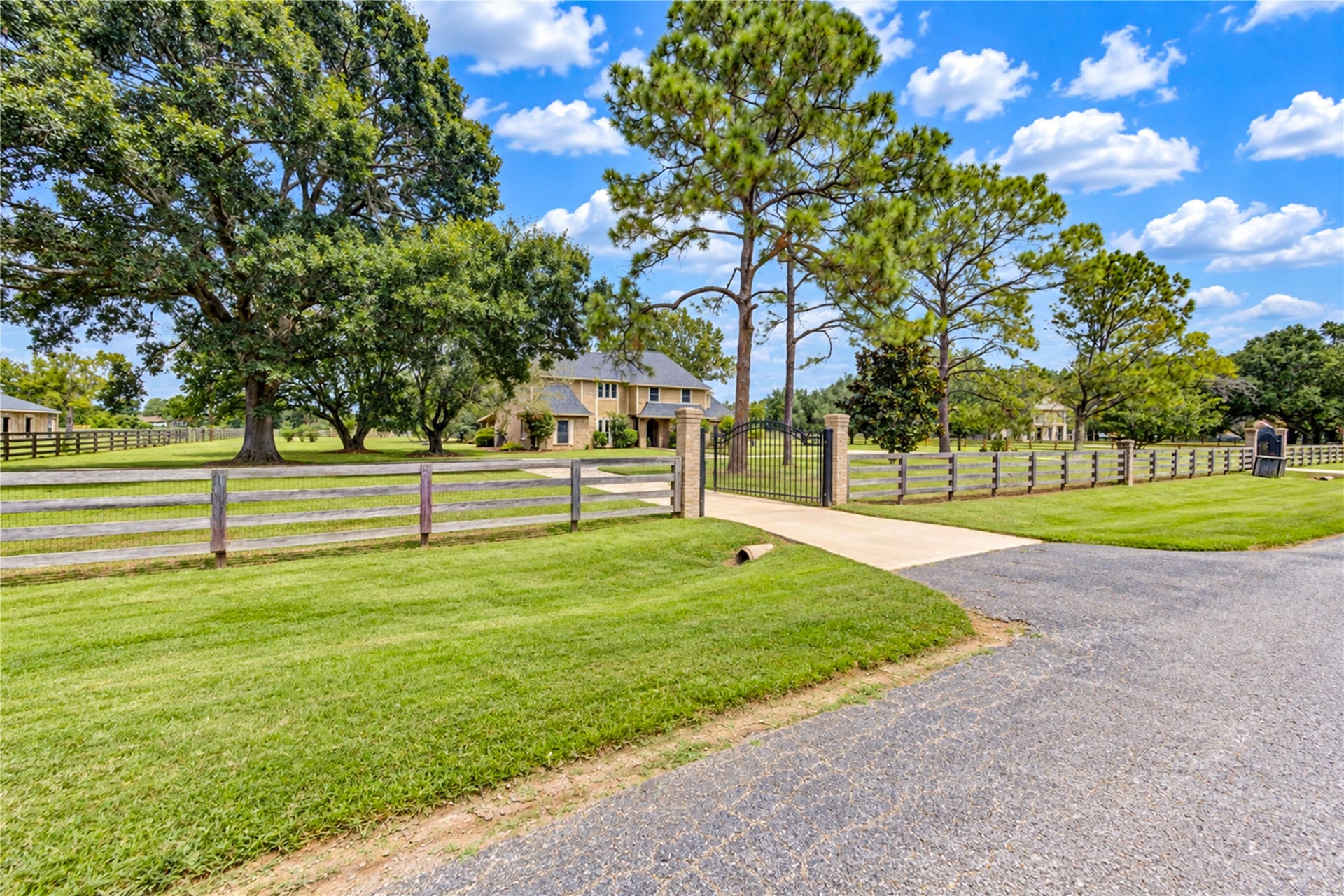 This charming country estate features two gated entrances, sprawling green lawns, and mature trees, offering privacy and tranquility.