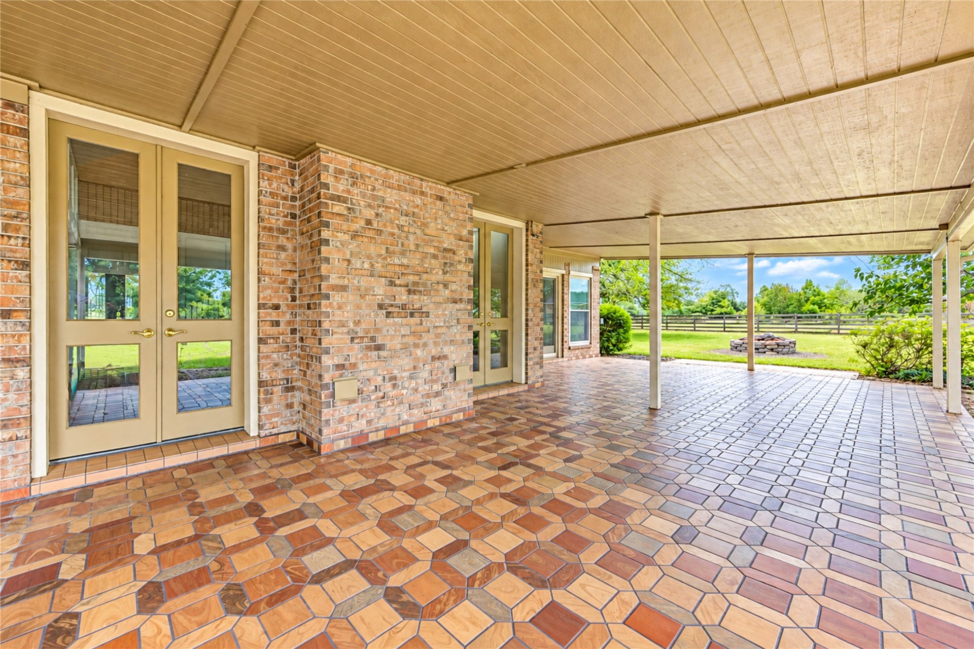 Spacious covered patio with stylish tile flooring and scenic backyard views, perfect for outdoor entertaining.