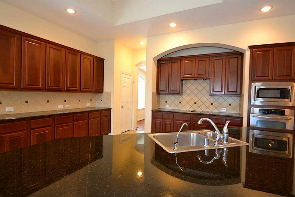 6606 Cadogan Court, Sugar Land, TX 77479 KITCHEN featuring elegant granite countertops, stylish tile accents, ample cabinetry, and plenty of space for cooking, gathering, and entertaining.