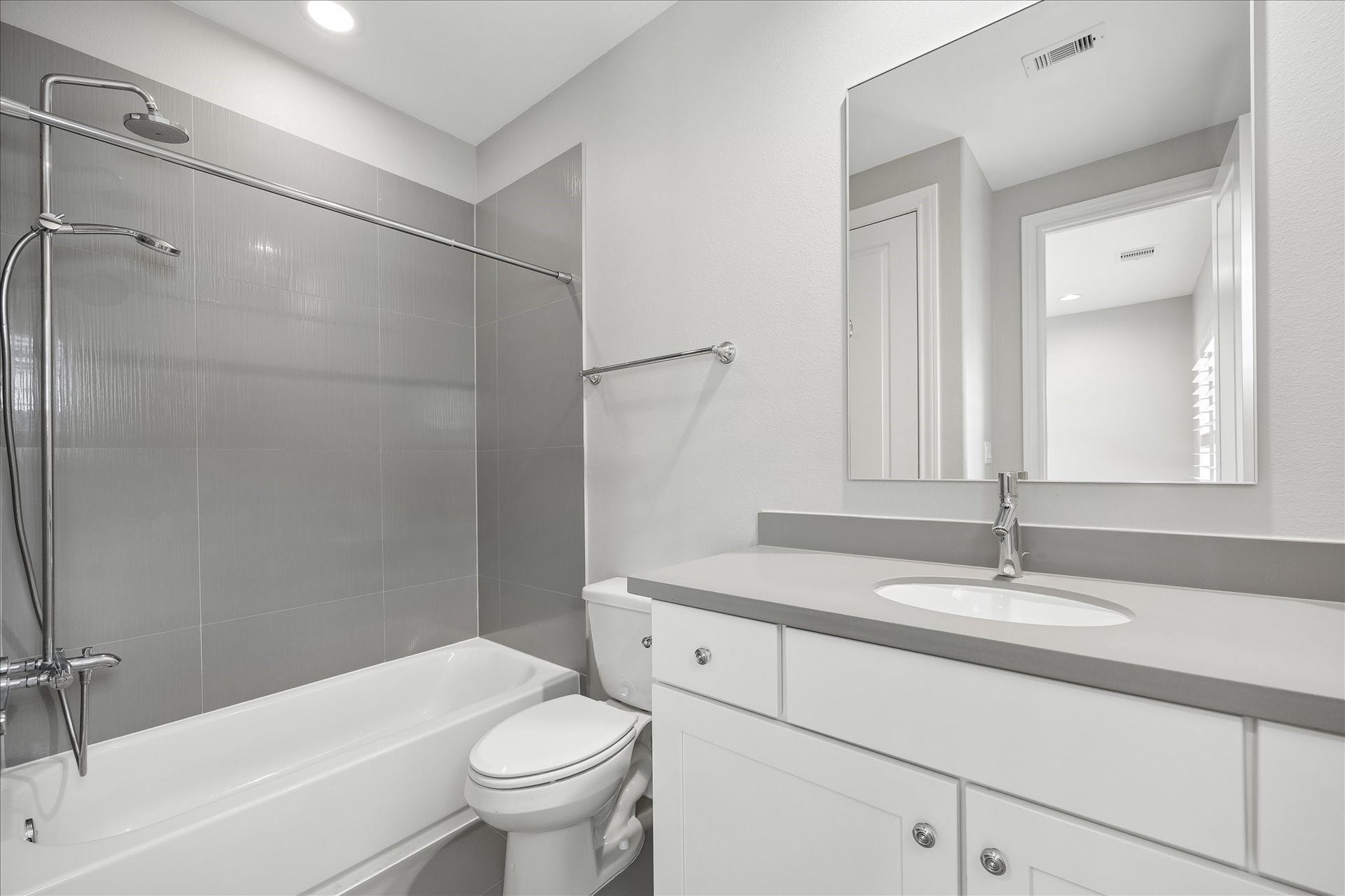 6029 Matthew Oaks Place, Houston, TX 77007 En-suite bath for 3rd floor bedroom. Modern bathroom featuring sleek gray tile, a spacious bathtub with an overhead shower, and a stylish vanity with ample storage.