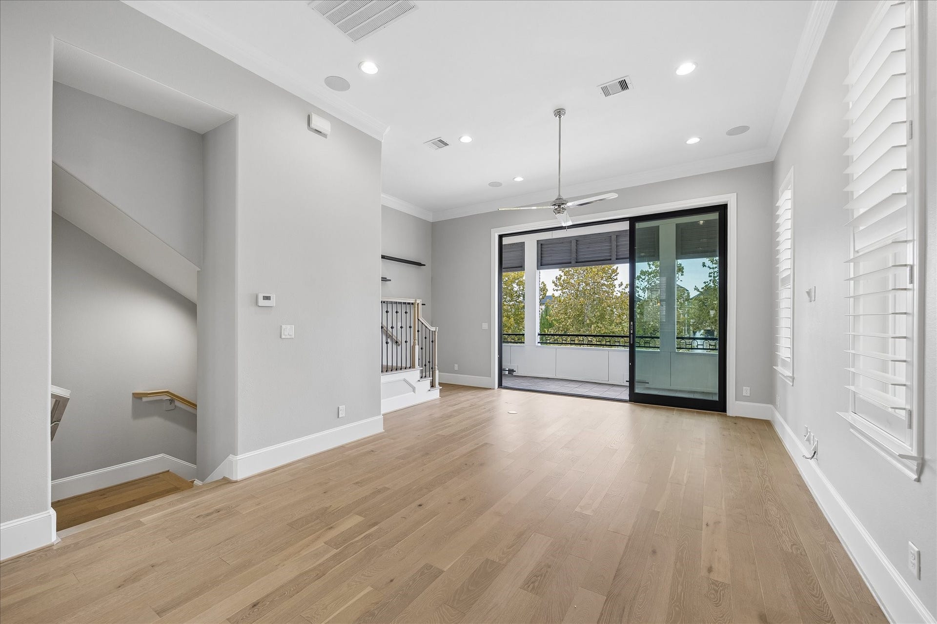 6029 Matthew Oaks Place, Houston, TX 77007 Bright and spacious living area with sleek hardwood floors, recessed lighting, and large sliding glass doors leading to a balcony with harmonious views of water, perfect for indoor-outdoor living.