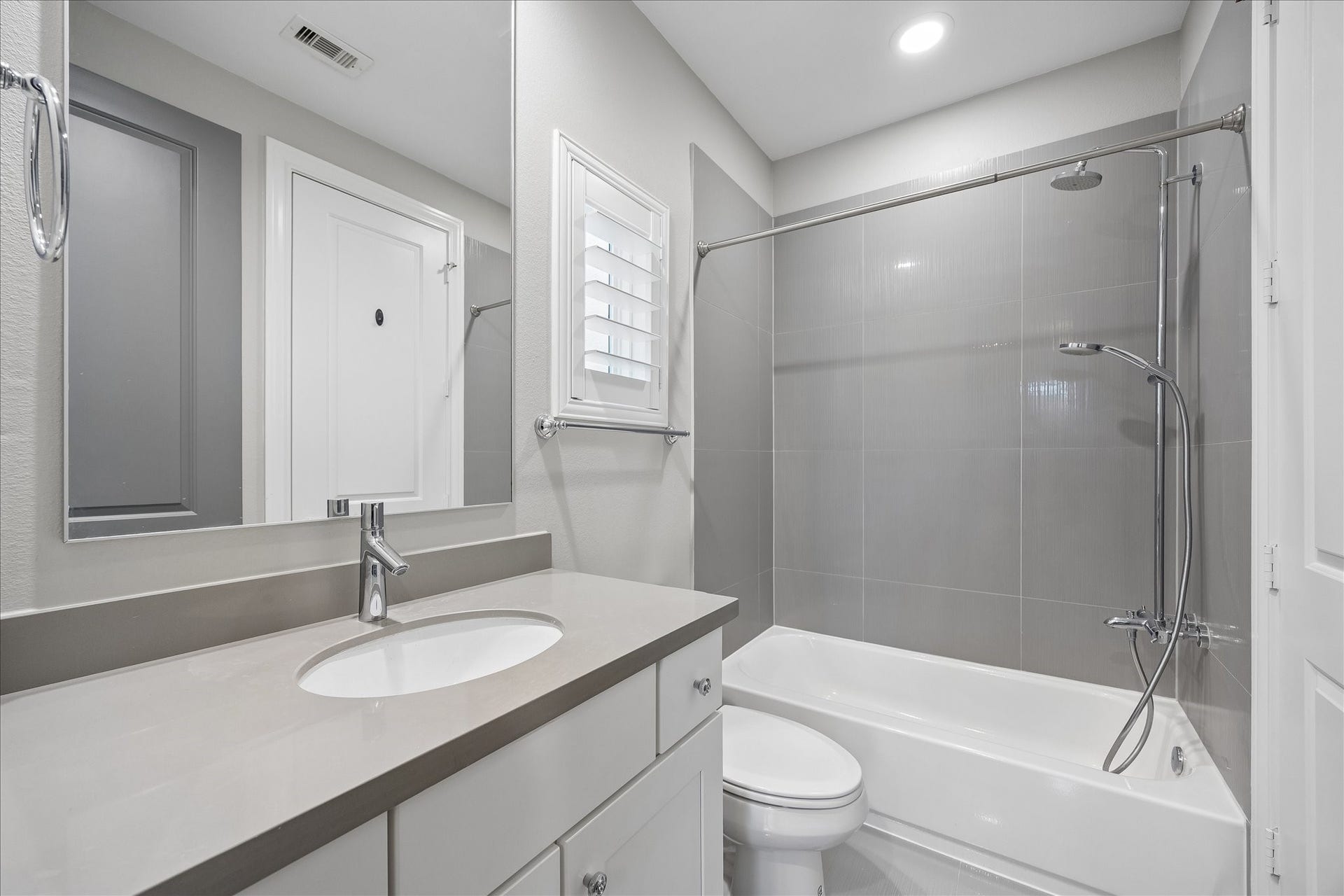 6029 Matthew Oaks Place, Houston, TX 77007 En-suite bath in first floor bedroom. Modern bathroom featuring sleek gray tiles, a spacious vanity with an undermount sink, and a pristine bathtub-shower combo, complemented by soft lighting for a clean and inviting atmosphere.