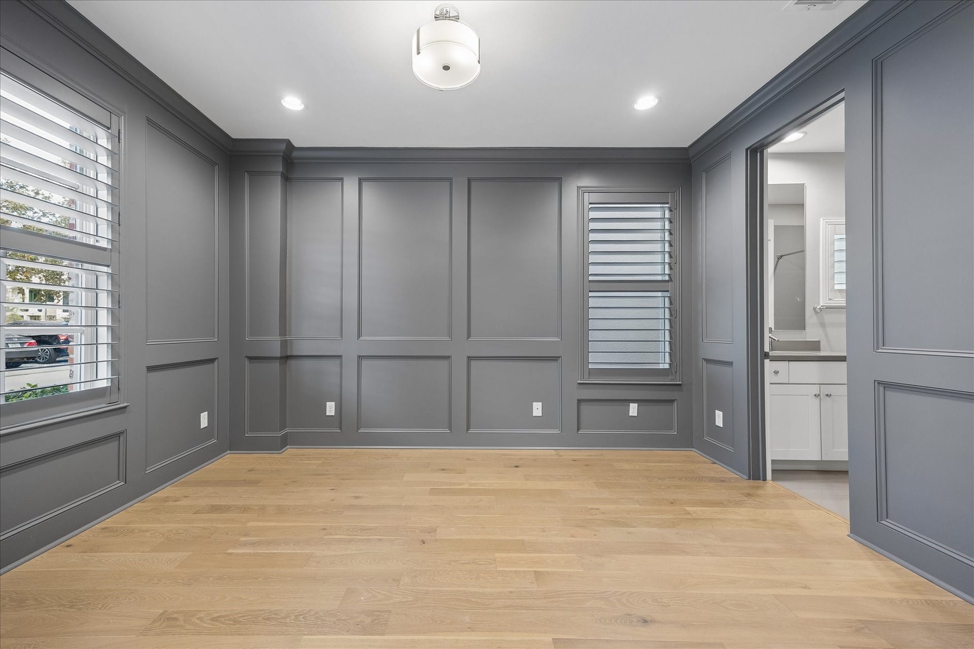 6029 Matthew Oaks Place, Houston, TX 77007 Elegant room with rich gray paneled walls, hardwood floors, and stylish plantation shutters, offering a modern and sophisticated ambiance.