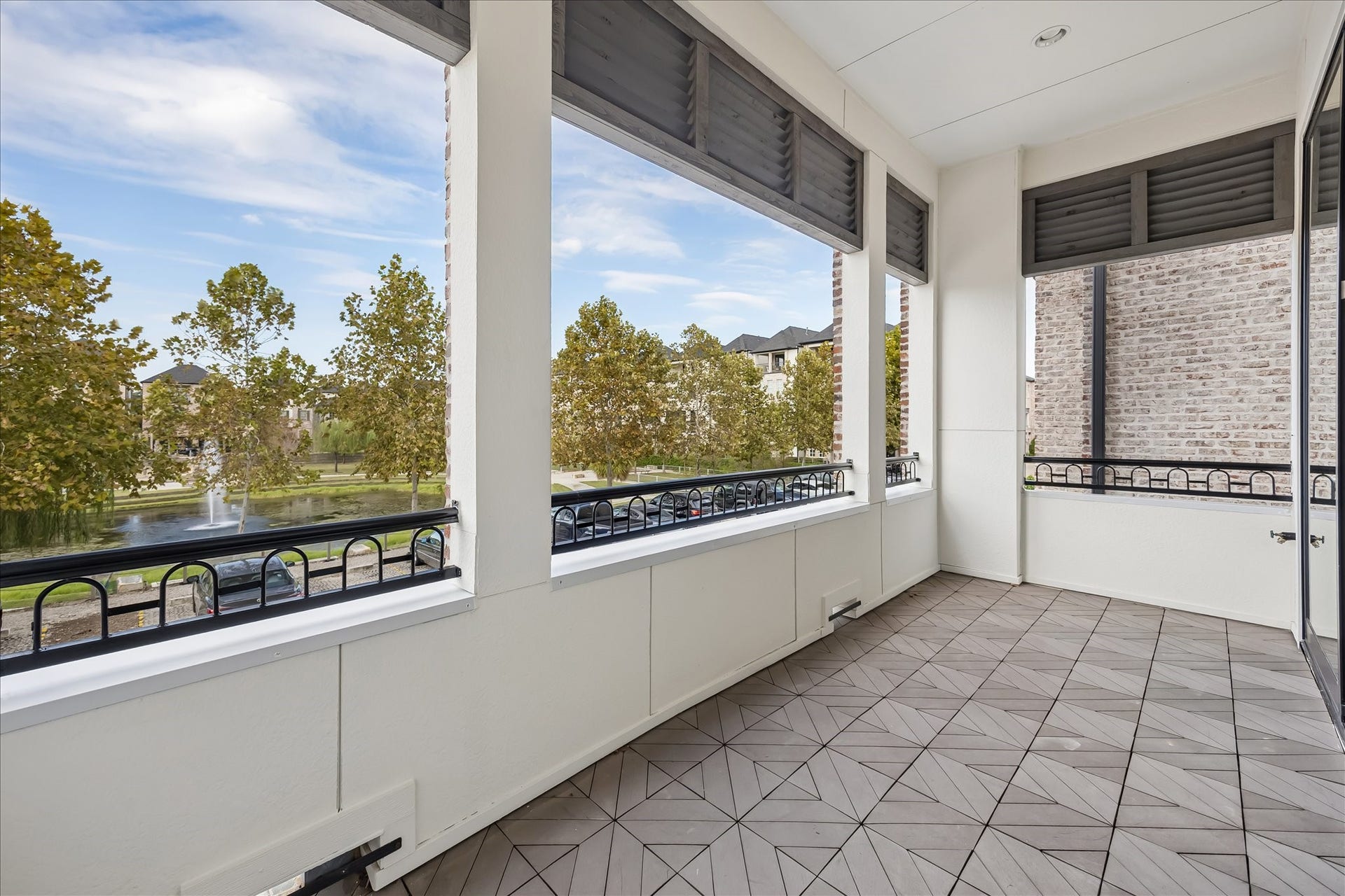6029 Matthew Oaks Place, Houston, TX 77007 Spacious covered balcony with elegant tile flooring offers scenic views of mature trees and a serene fountain, perfect for relaxation and outdoor enjoyment. Large enough for table, chairs, and entertainment with great views.