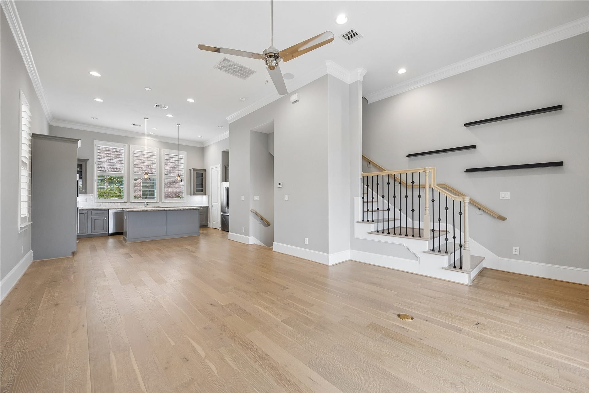 6029 Matthew Oaks Place, Houston, TX 77007 Spacious open-concept living area with elegant hardwood floors, modern kitchen with sleek cabinetry and large island, and a stylish staircase with contemporary railing design.