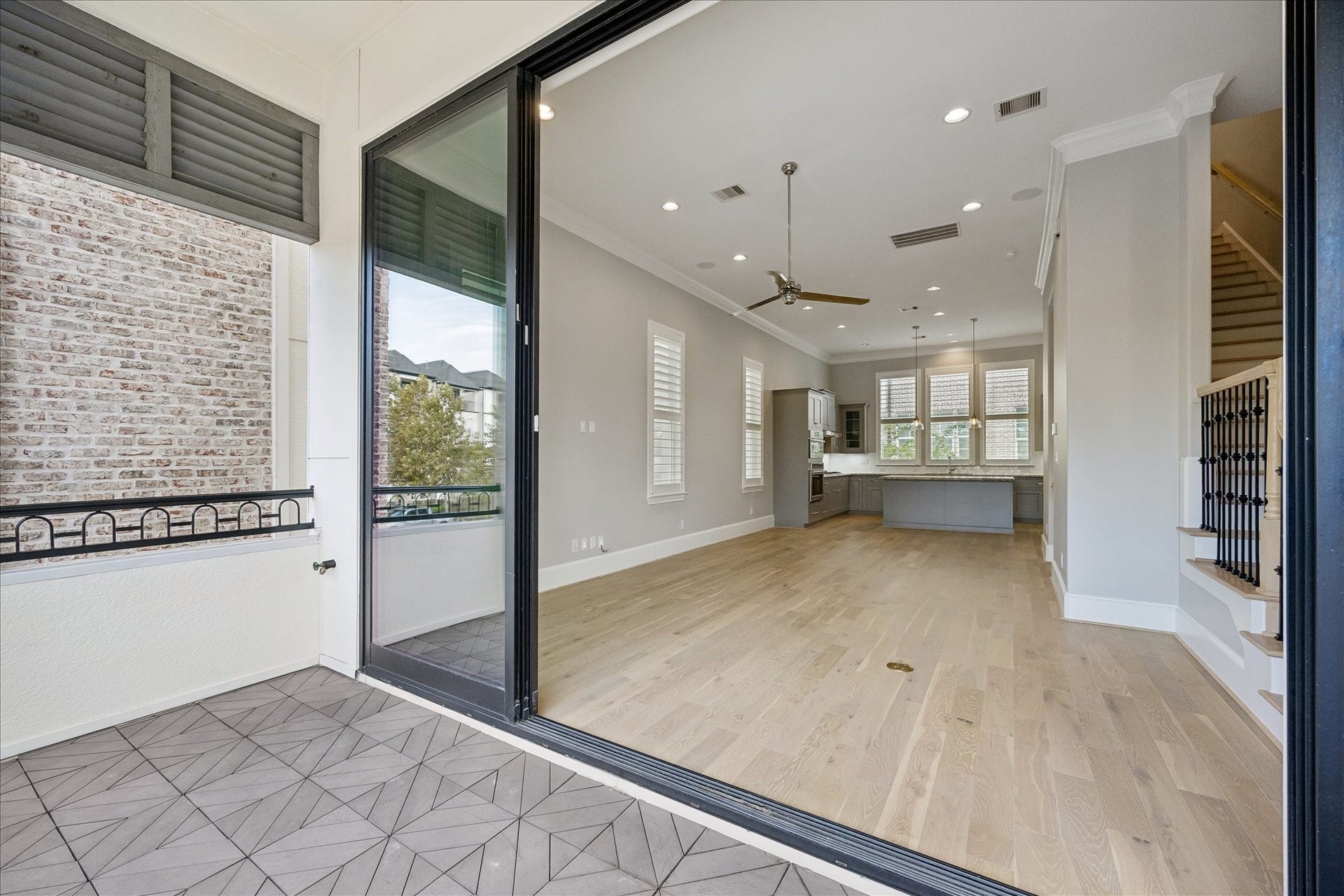 6029 Matthew Oaks Place, Houston, TX 77007 Spacious open-plan living area with elegant hardwood floors, modern kitchen, and ample natural light, seamlessly extending to a charming tiled balcony.