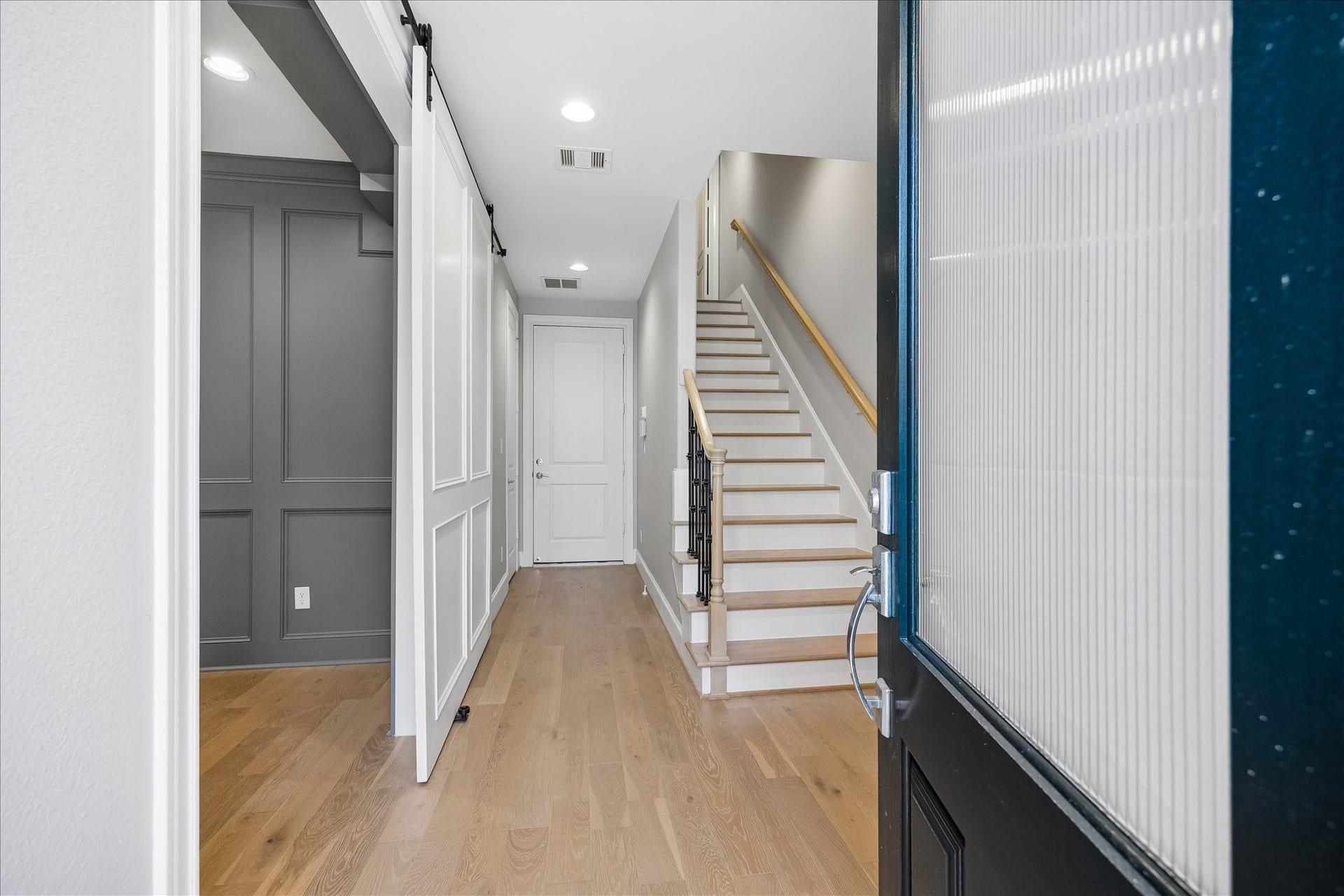 6029 Matthew Oaks Place, Houston, TX 77007 Inviting entrance with sleek hardwood floors, a modern sliding barn door leading to downstairs bedroom or office, and a staircase leading to the upper level.