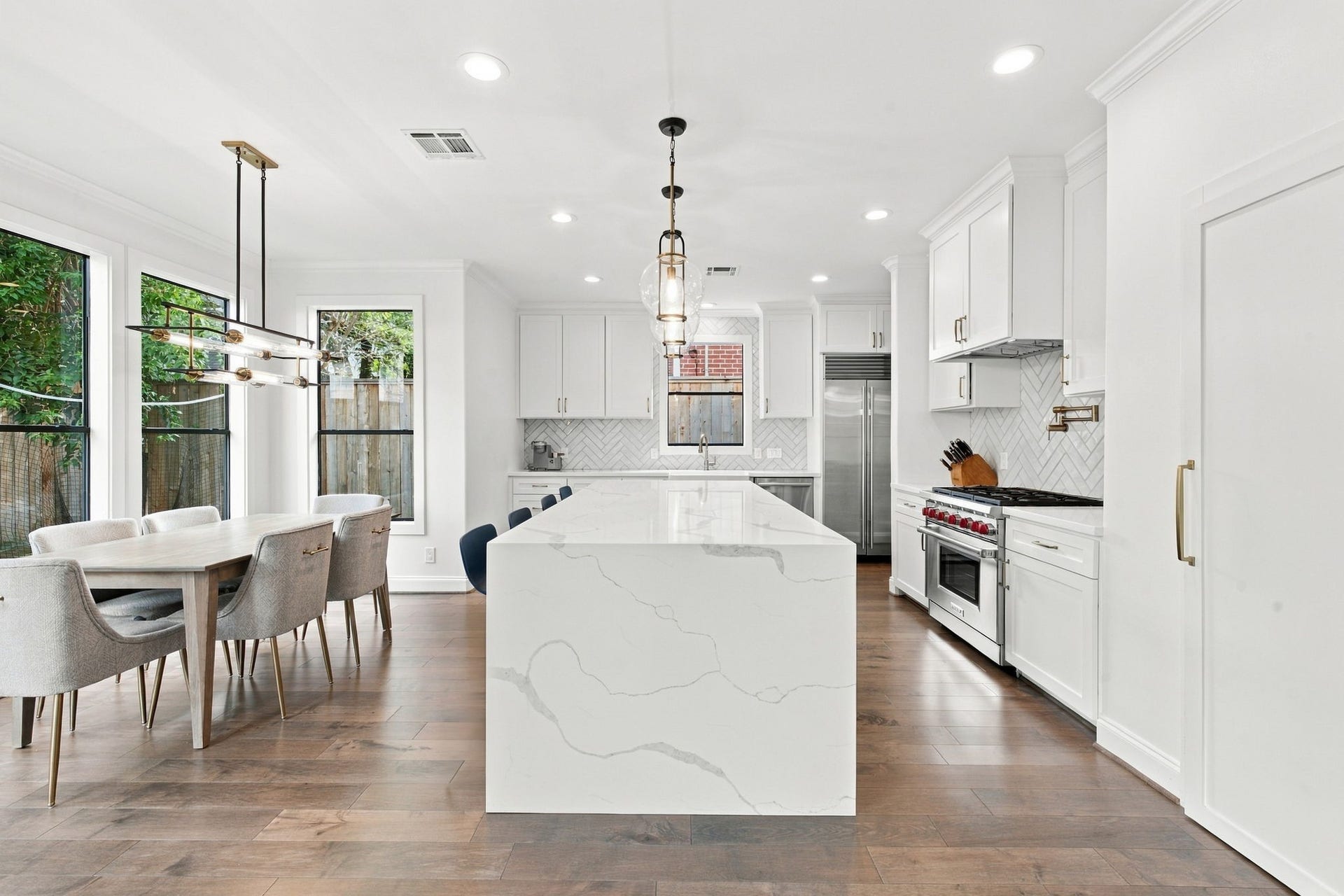 Gorgeous chef's kitchen showcases a spectacular oversized waterfall island w/beautiful, veined countertops, custom white cabinetry, stainless steel appliances & elegant pendant lighting. The adjoining breakfast area is surrounded by large windows overlooking the backyard, creating a bright & inviting space for everyday dining.
