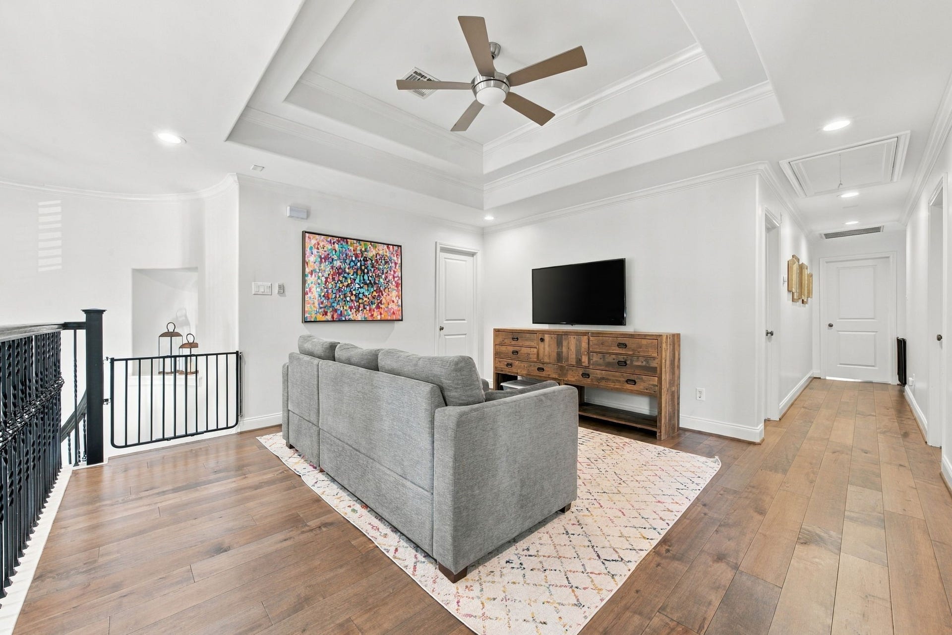 Spacious upstairs game room overlooking the entry, featuring hardwood floors, tray ceiling w/ceiling fan, recessed lighting & an open layout.