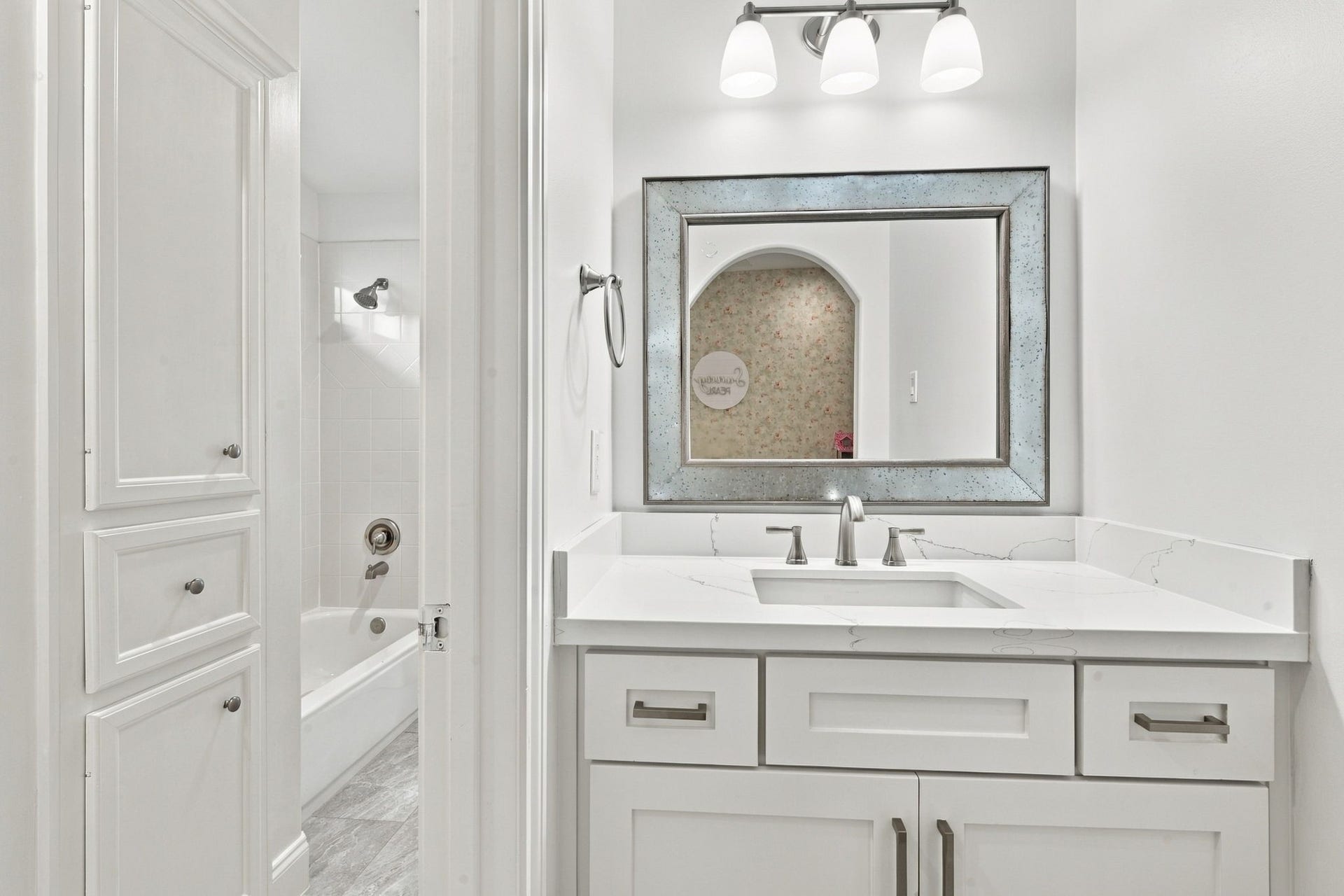 Opposite side of the Hollywood bath features a separate vanity w/stone countertop, undermount sink, framed mirror & built-in cabinetry for storage. Shared tub/shower area completes this functional bathroom layout.