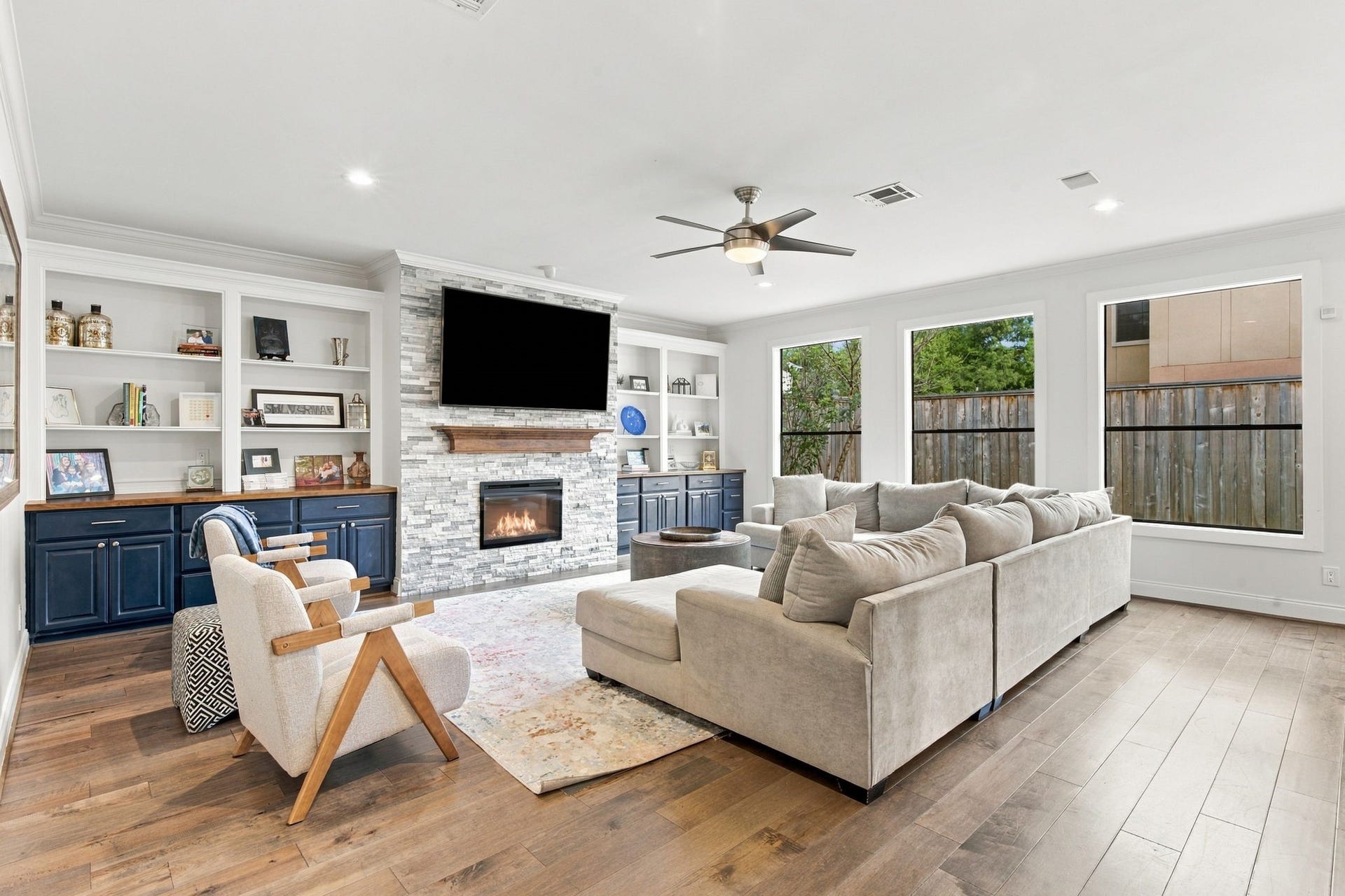 Spacious living room offers a wonderful gathering space featuring beautiful hardwood floors, a striking stone-surround fireplace w/wood mantel & custom built-ins on either side. Large windows overlook the backyard, filling the room w/natural light, while recessed lighting & a ceiling fan complete this inviting space.