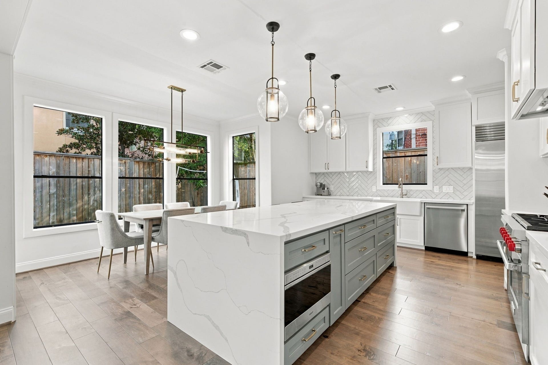 Another perspective highlights the impressive center island featuring contrasting cabinetry, extensive drawer storage, built-in microwave & beautiful countertops. The kitchen also features a farmhouse sink, stainless steel dishwasher, herringbone tile backsplash & abundant natural light throughout.