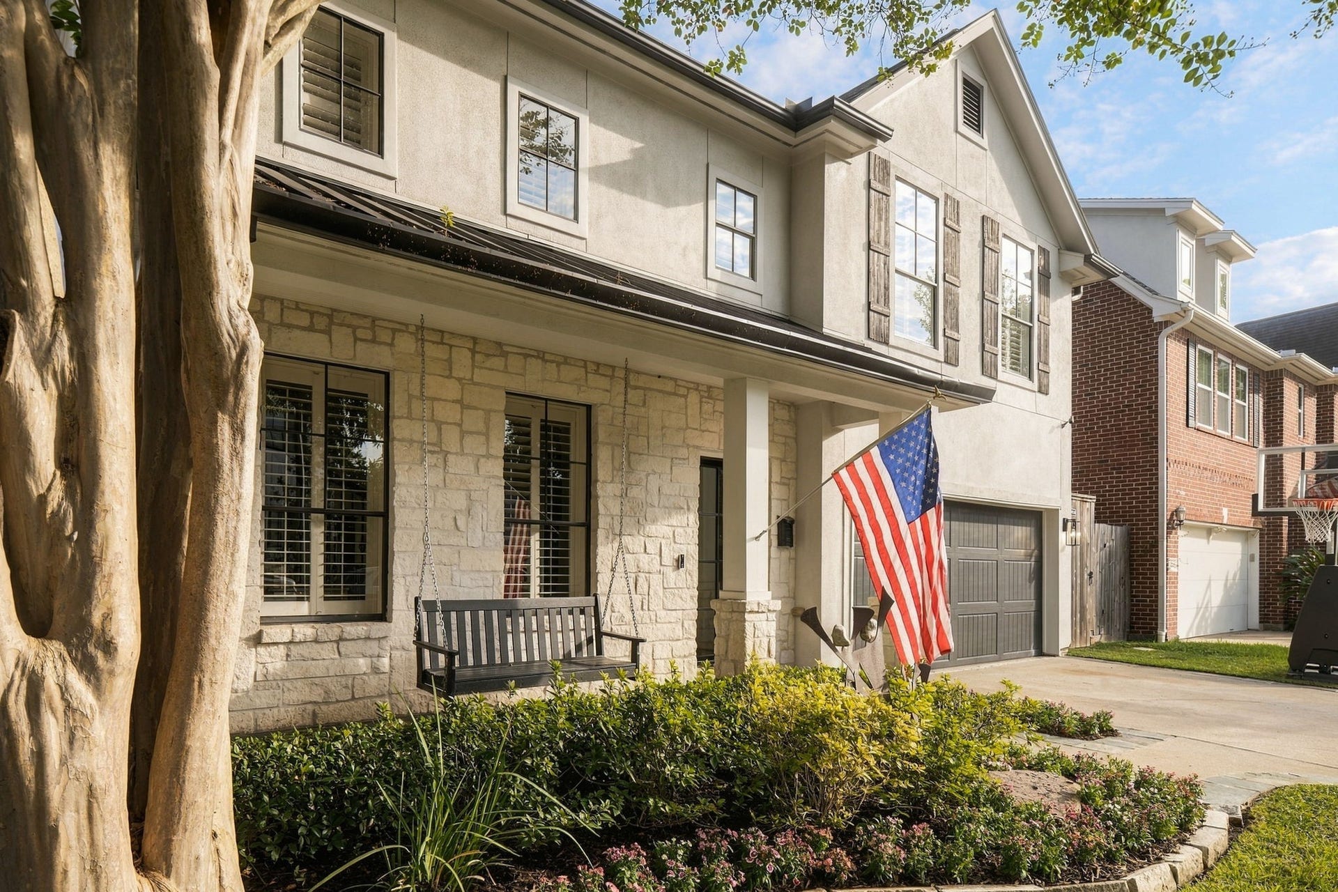 Enjoy the inviting covered front porch featuring a classic hanging porch swing, beautiful stone accents & windows w/plantation shutters. Lush landscaping & colorful flower beds enhance this welcoming outdoor space.