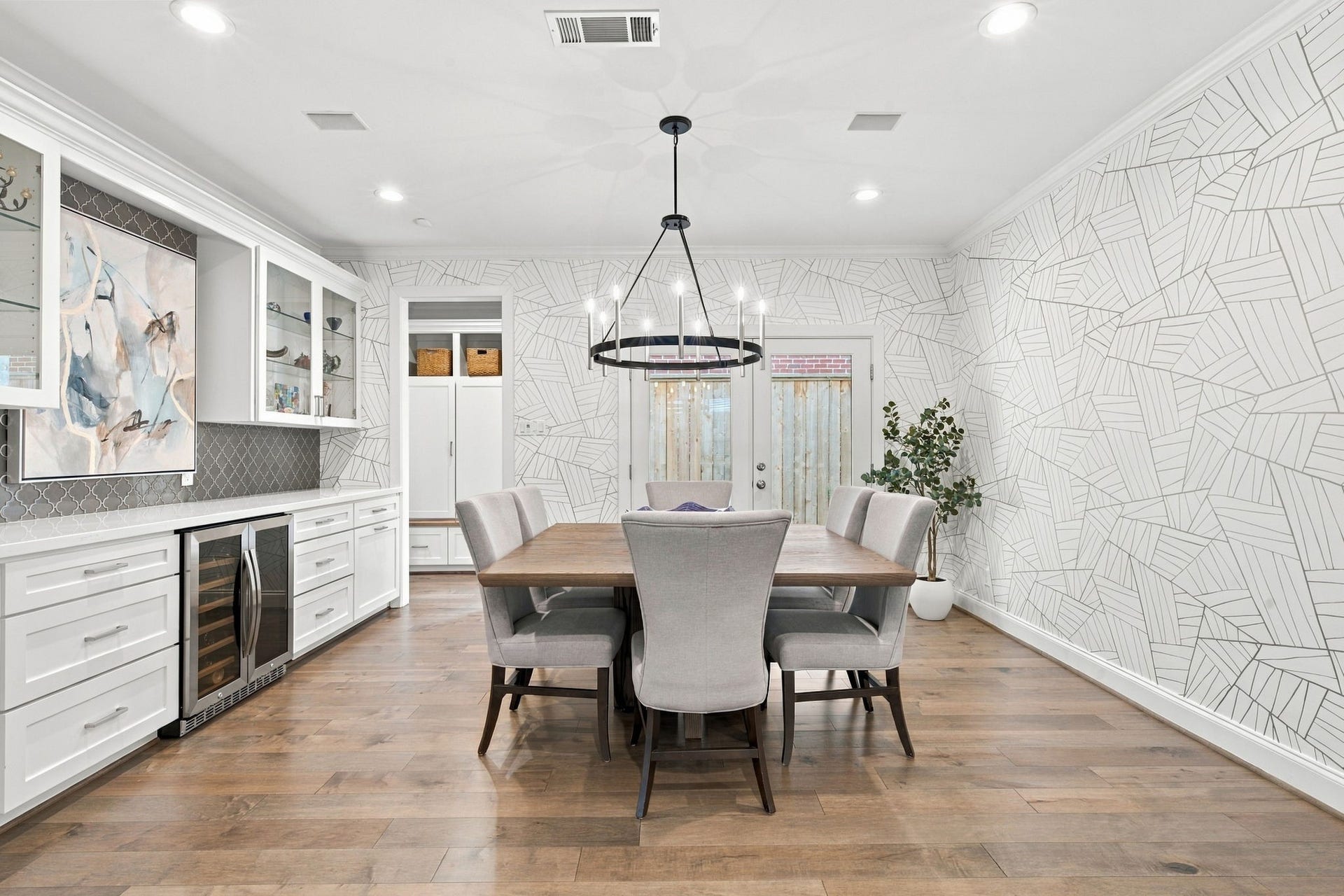 Beautiful formal dining room showcases gorgeous hardwood floors, eye-catching geometric wallpaper & a striking circular chandelier. Custom built-in cabinetry w/glass-front display cabinets, decorative tile backsplash, wine refrigerator & extensive storage creates a wonderful setting for entertaining.