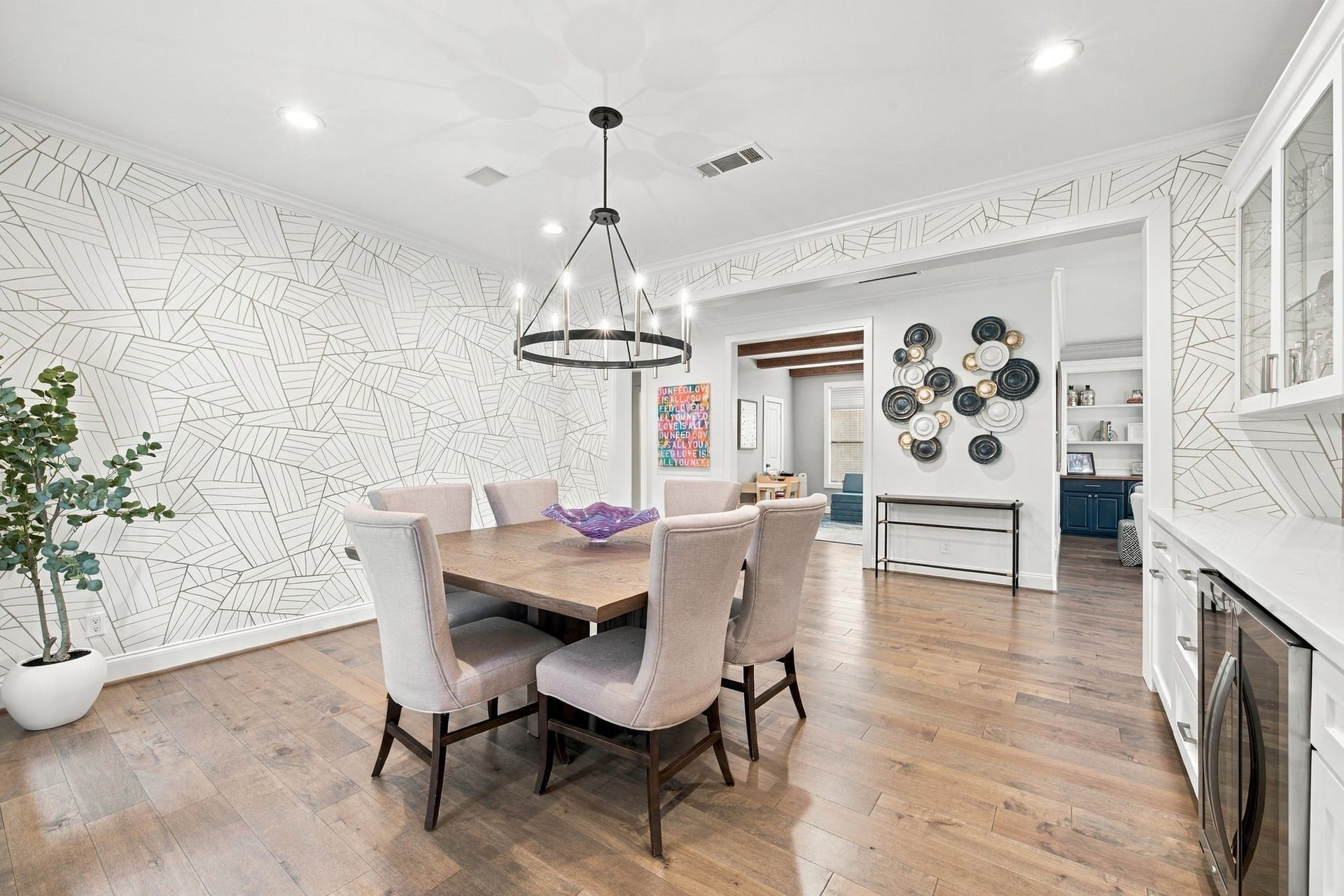 Spacious dining room comfortably accommodates a large dining table & flows seamlessly to the living room and kitchen. The distinctive wallpaper, beautiful millwork & open layout make this an impressive space for gatherings & everyday dining.