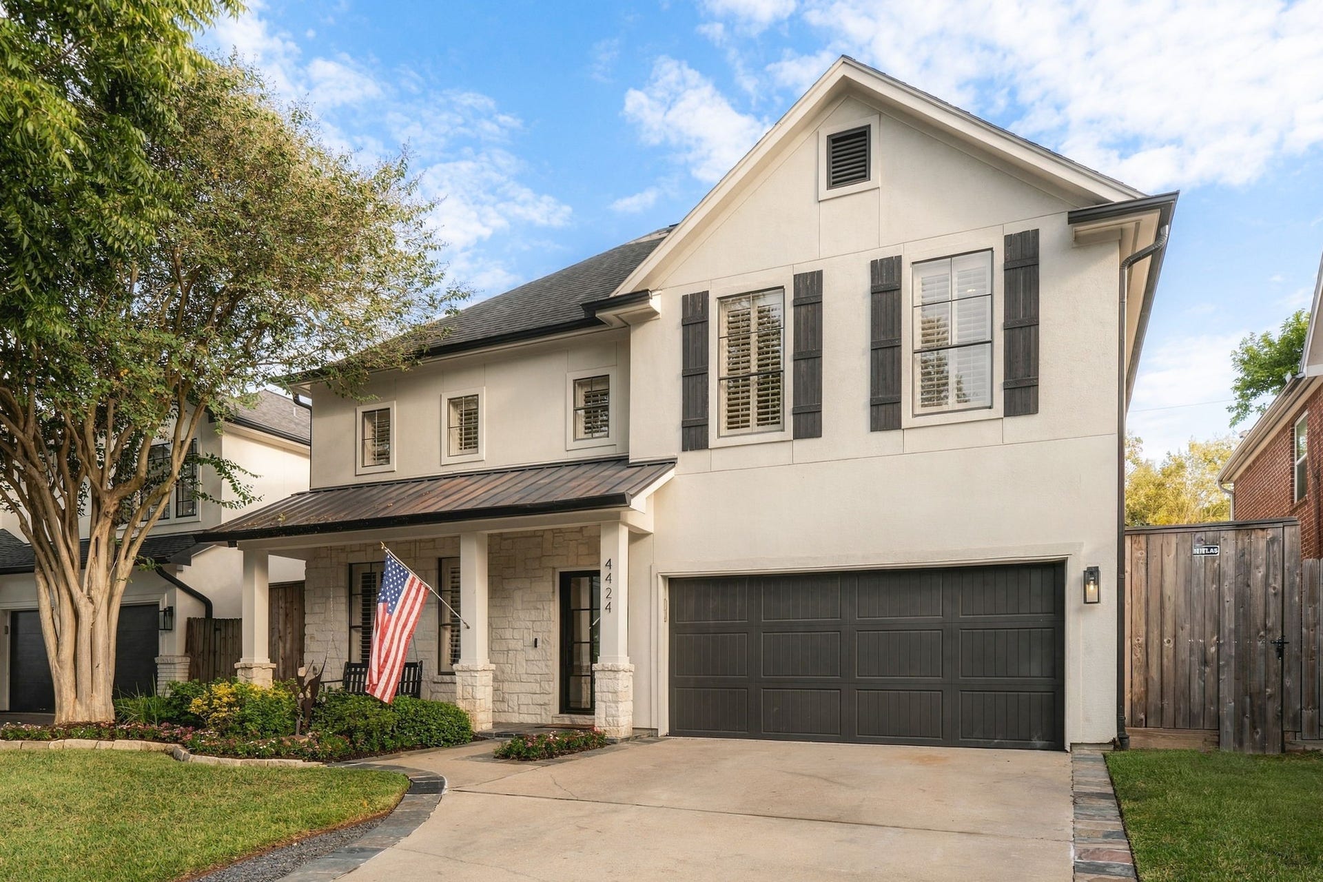 Another perspective showcasing the home's attractive architectural details, metal porch roof, decorative shutters, spacious driveway & distinctive paneled garage door that complements the home's exterior.