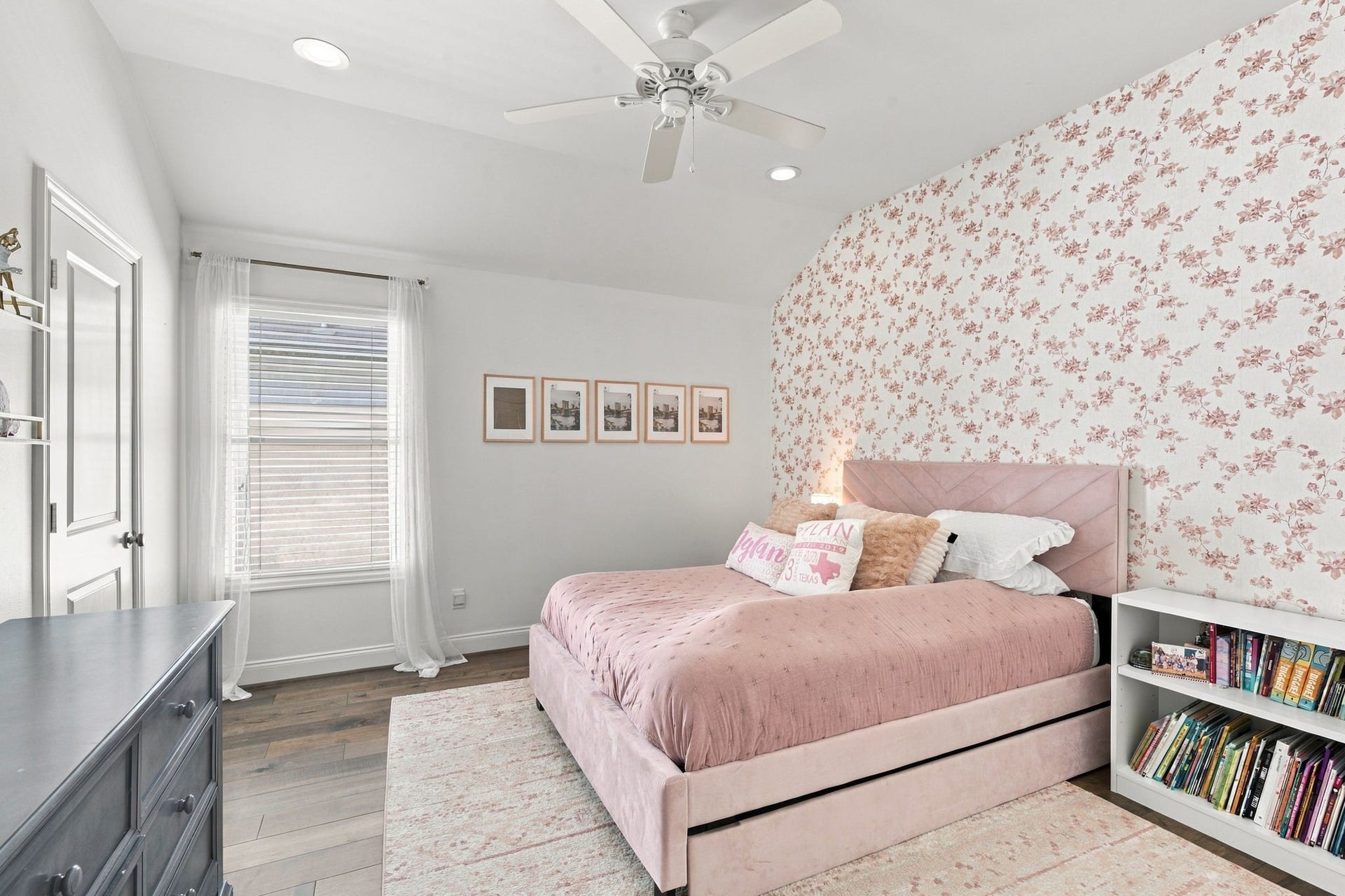 Spacious secondary bedroom featuring beautiful hardwood floors, a vaulted ceiling, recessed lighting & ceiling fan. Large window brings in natural light, while the floral accent wall adds a lovely touch of character.