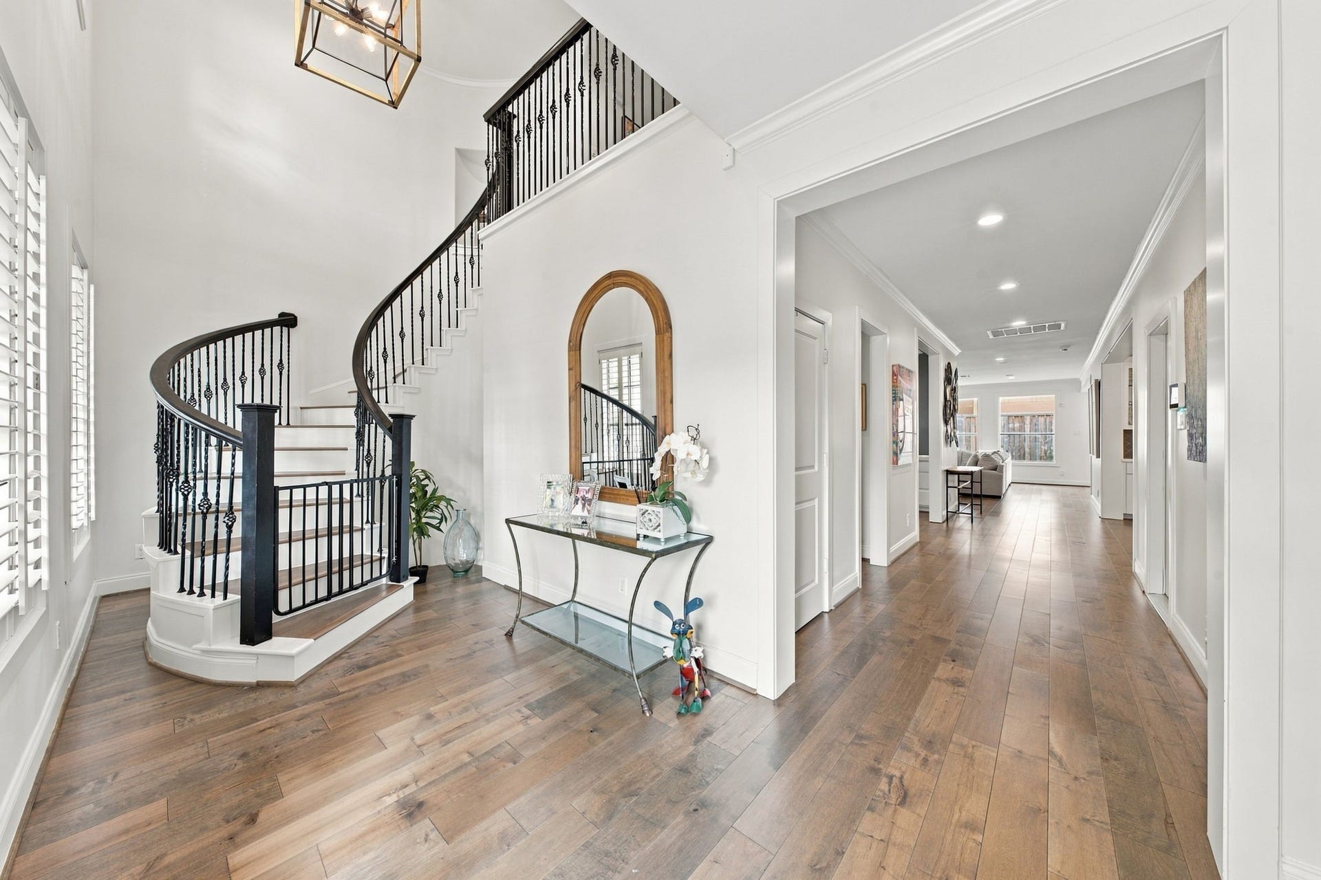 Impressive two-story entry welcomes you w/beautiful hardwood floors, soaring ceilings & a stunning curved staircase featuring wrought iron balusters & wood handrail. Abundant natural light, plantation shutters, elegant crown molding & a statement lantern chandelier enhance this inviting space, which opens to the main hallway leading to the living areas.