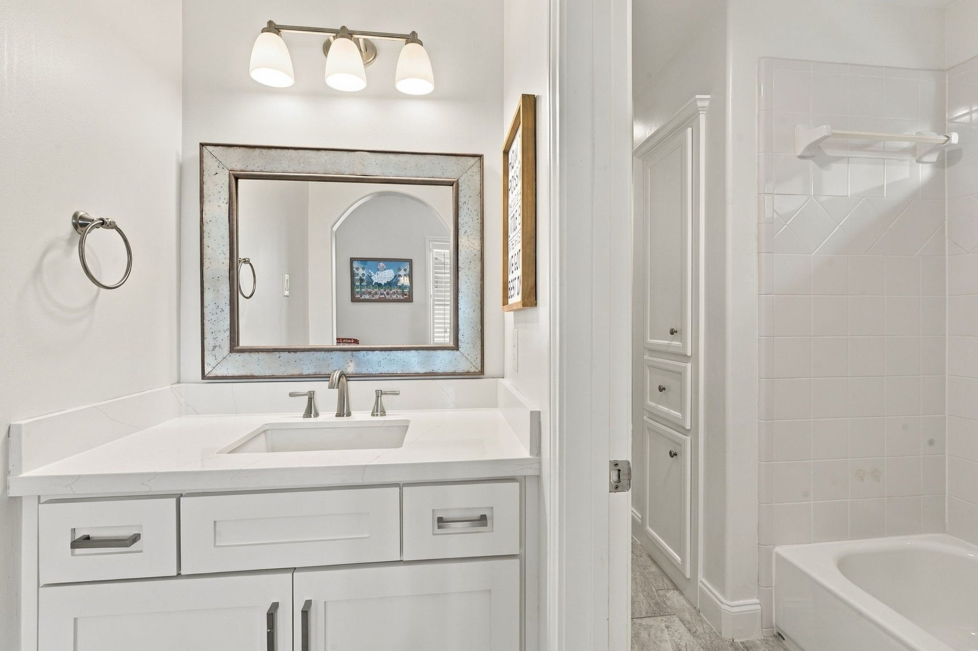 Hollywood-style bath featuring a vanity w/stone countertop, undermount sink, updated fixtures & cabinetry. Separate bathing area offers a tub/shower combination & additional built-in storage.