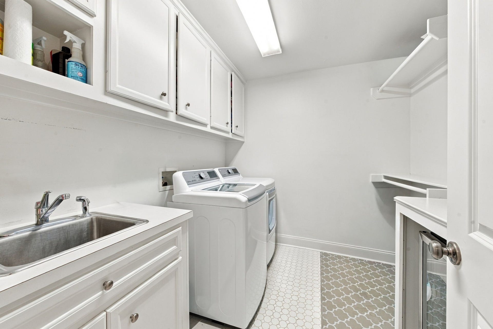 Spacious utility room featuring space for full size washer & dryer, utility sink, extensive cabinetry, built-in shelving, hanging space & additional countertops for folding and organization.