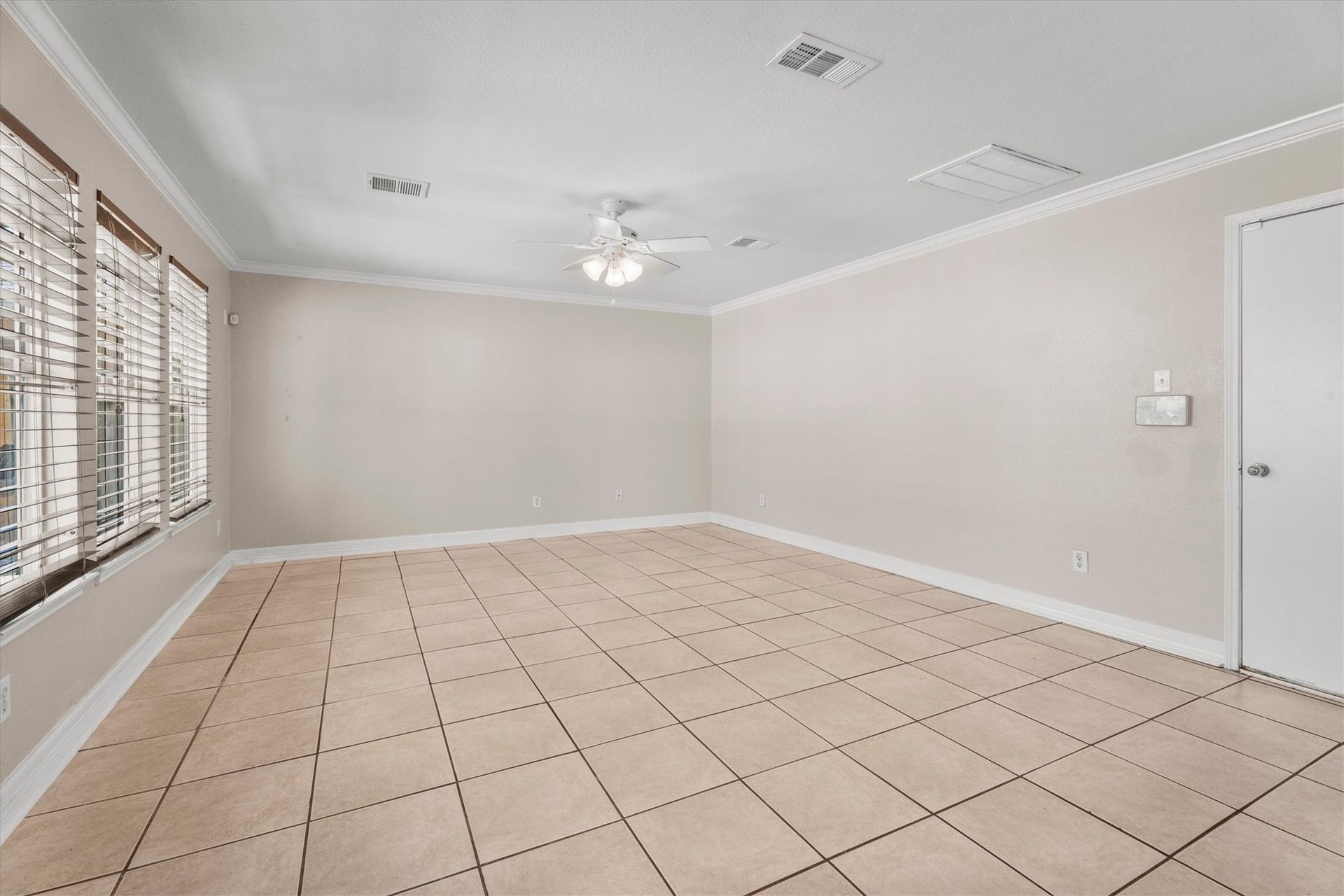 5918 Stirring Winds Lane, Houston, TX 77086 Large family room with tile flooring, abundant wall space for furniture placement, and multiple windows overlooking the backyard.