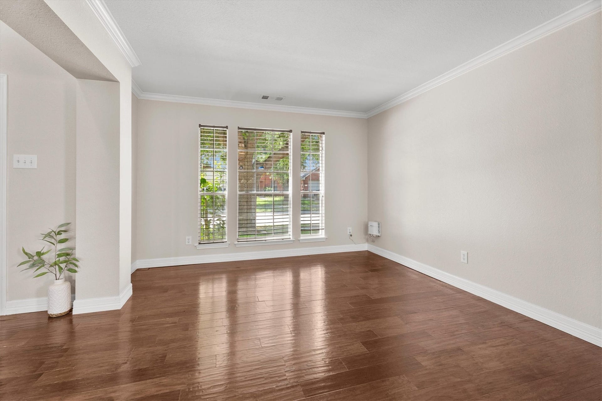 5918 Stirring Winds Lane, Houston, TX 77086 Spacious formal living room with large windows, wood flooring, and flexible space for entertaining or a home office.