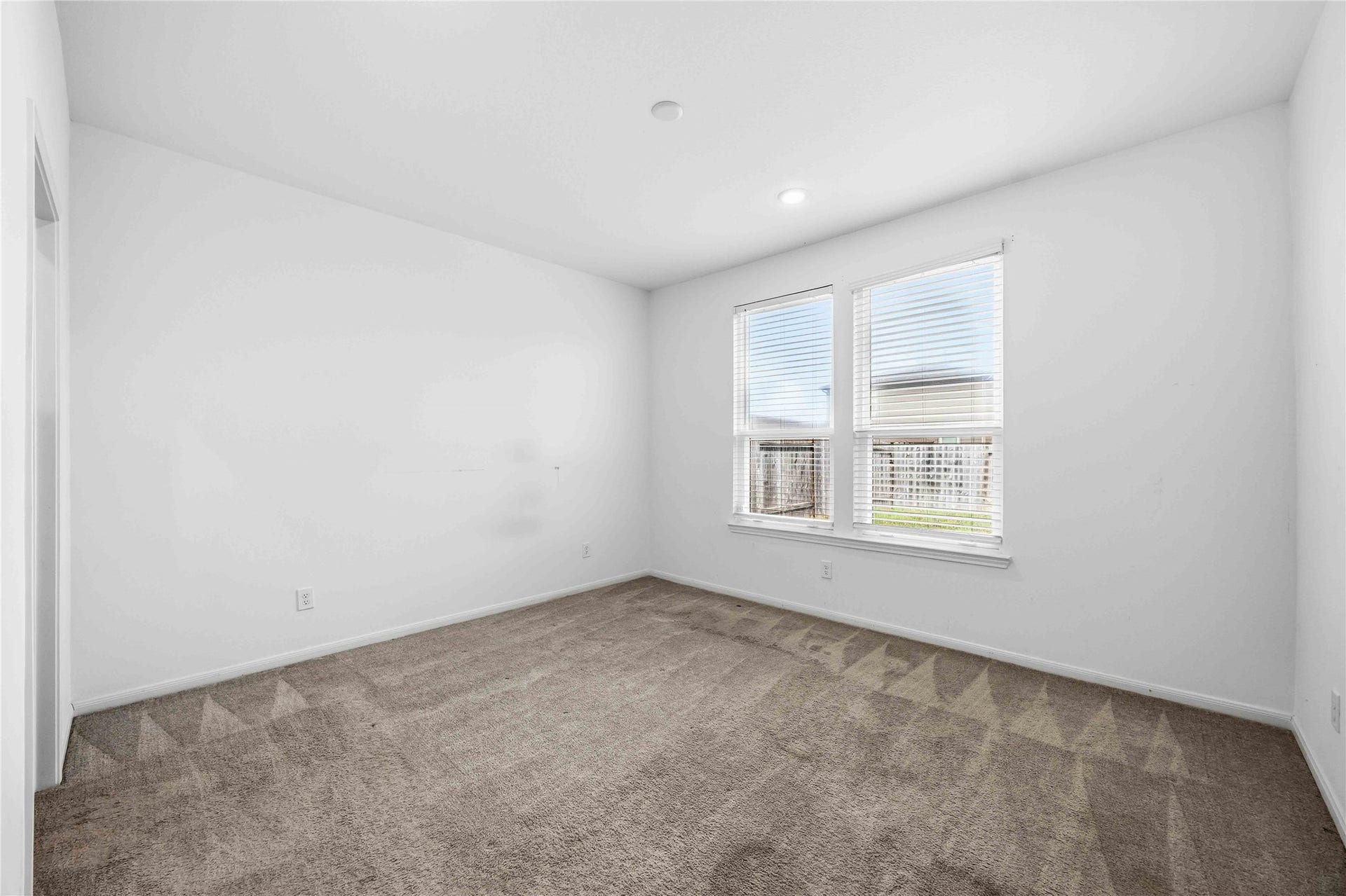Primary bedroom featuring paired windows and carpeting.