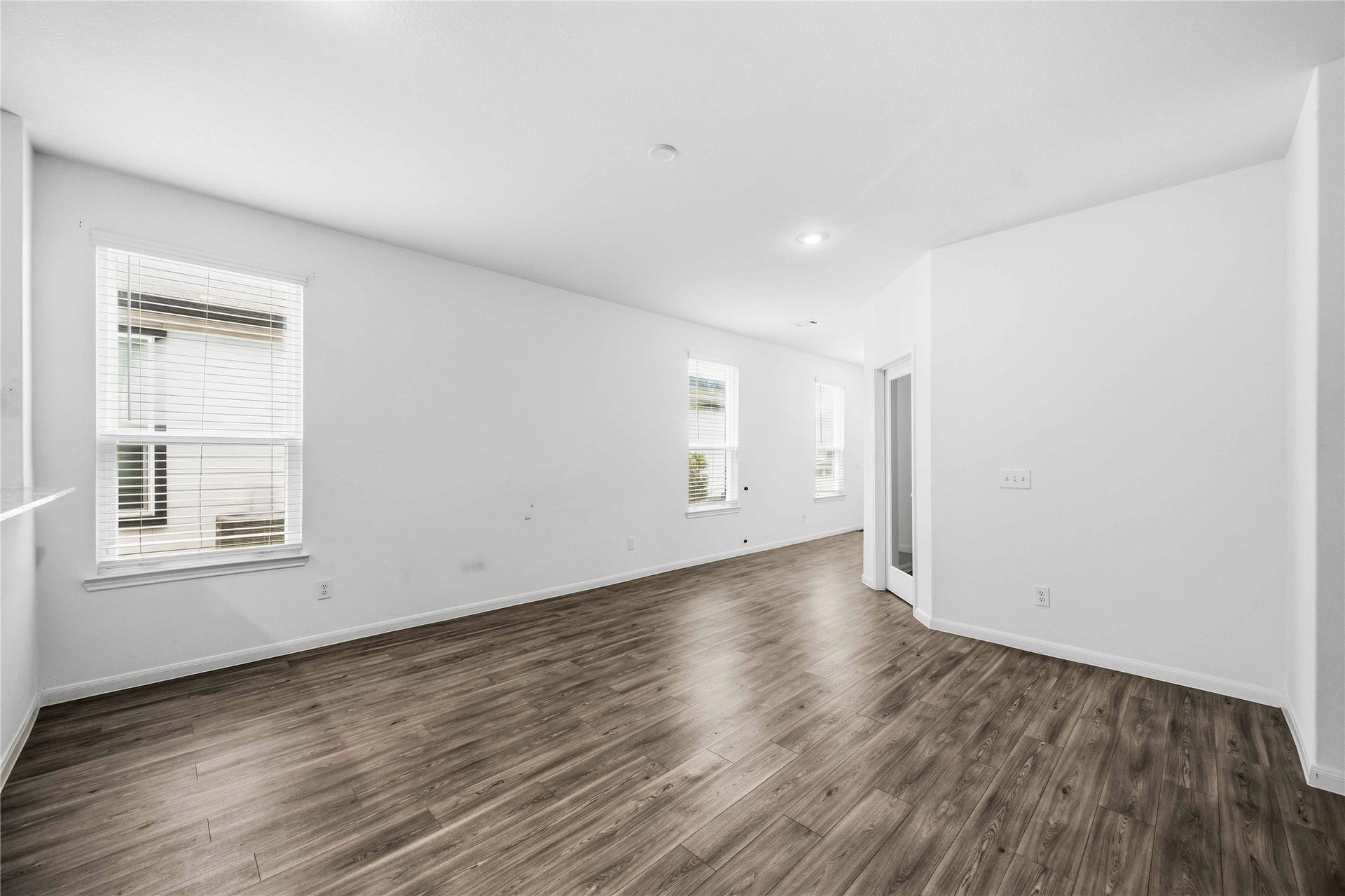 Bright living space with multiple windows and wood-look flooring.