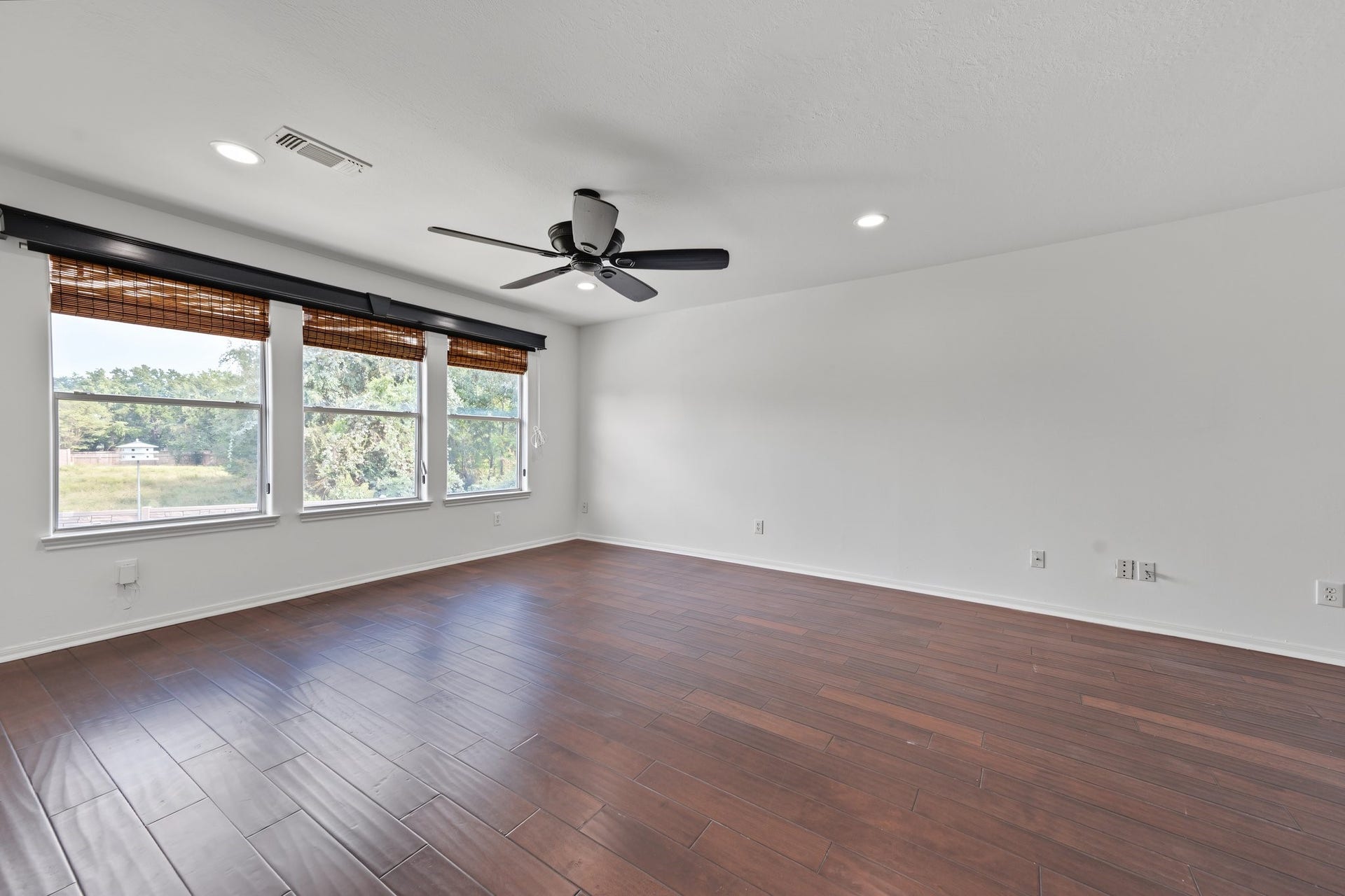 The game / media room is featuring rich hardwood floors, large windows with natural views, and a modern ceiling fan for comfort. Attached are electronic blackout shades, media room ready! All you need is your pool table, foosball table or big screen TV to watch those sports and movies!