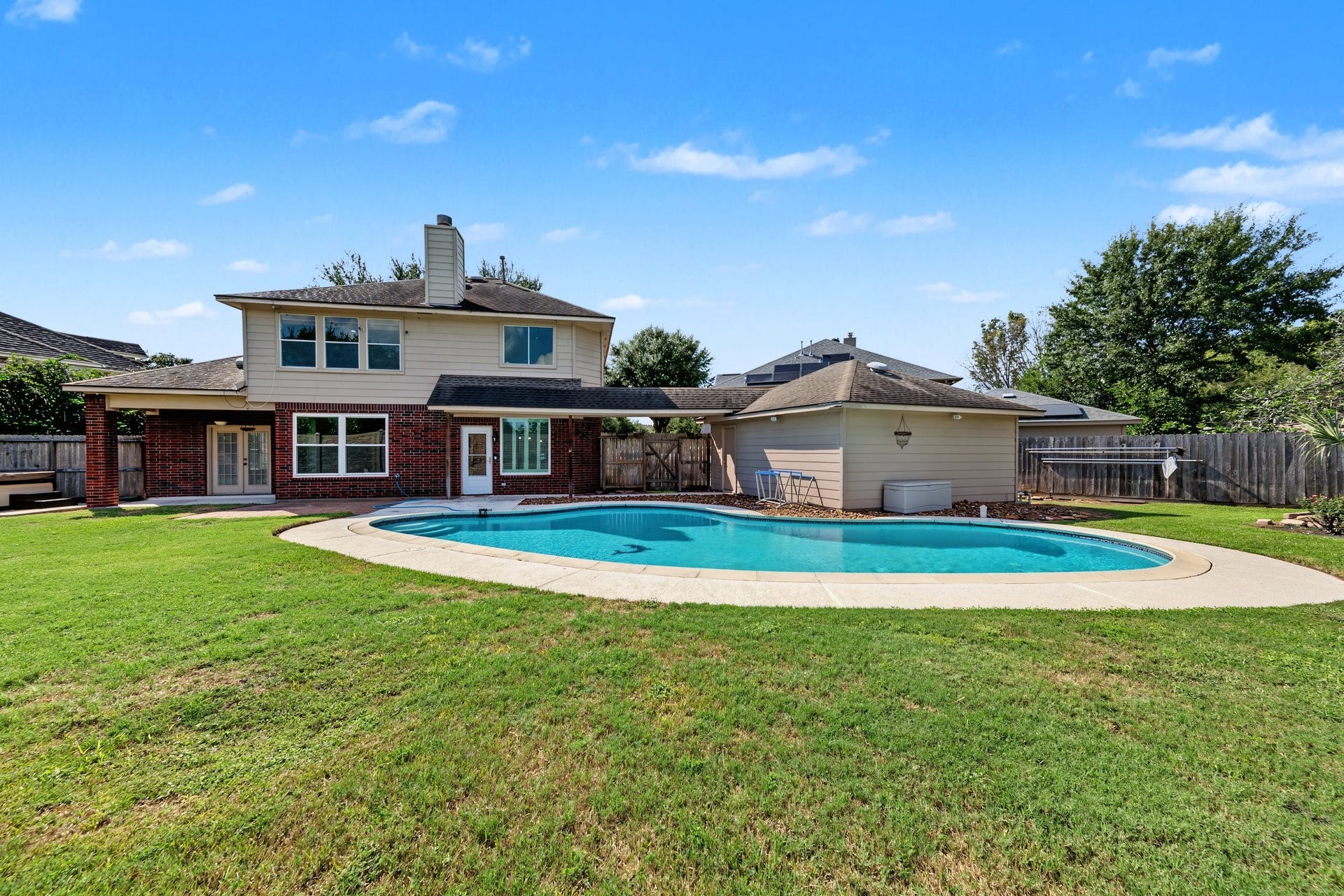 Spacious backyard featuring a sparkling pool, perfect for outdoor entertainment and relaxation, with the charming two-story home as a backdrop. Can you picture your family and friends barbqueing back here during a pool party? A splashing good time!