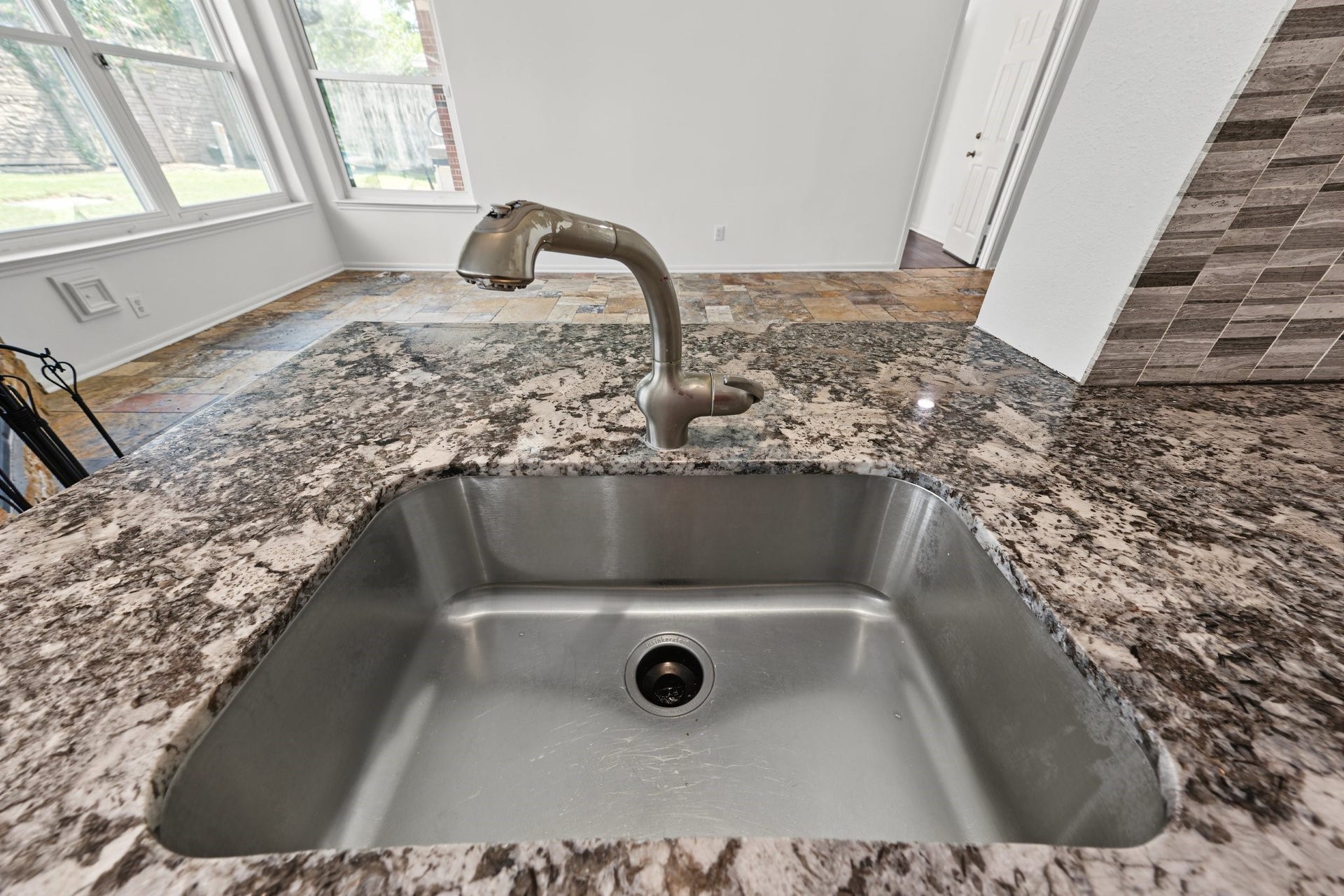The beautiful granite countertops are paired with a sleek stainless steel sink to create a sophisticated kitchen look.
