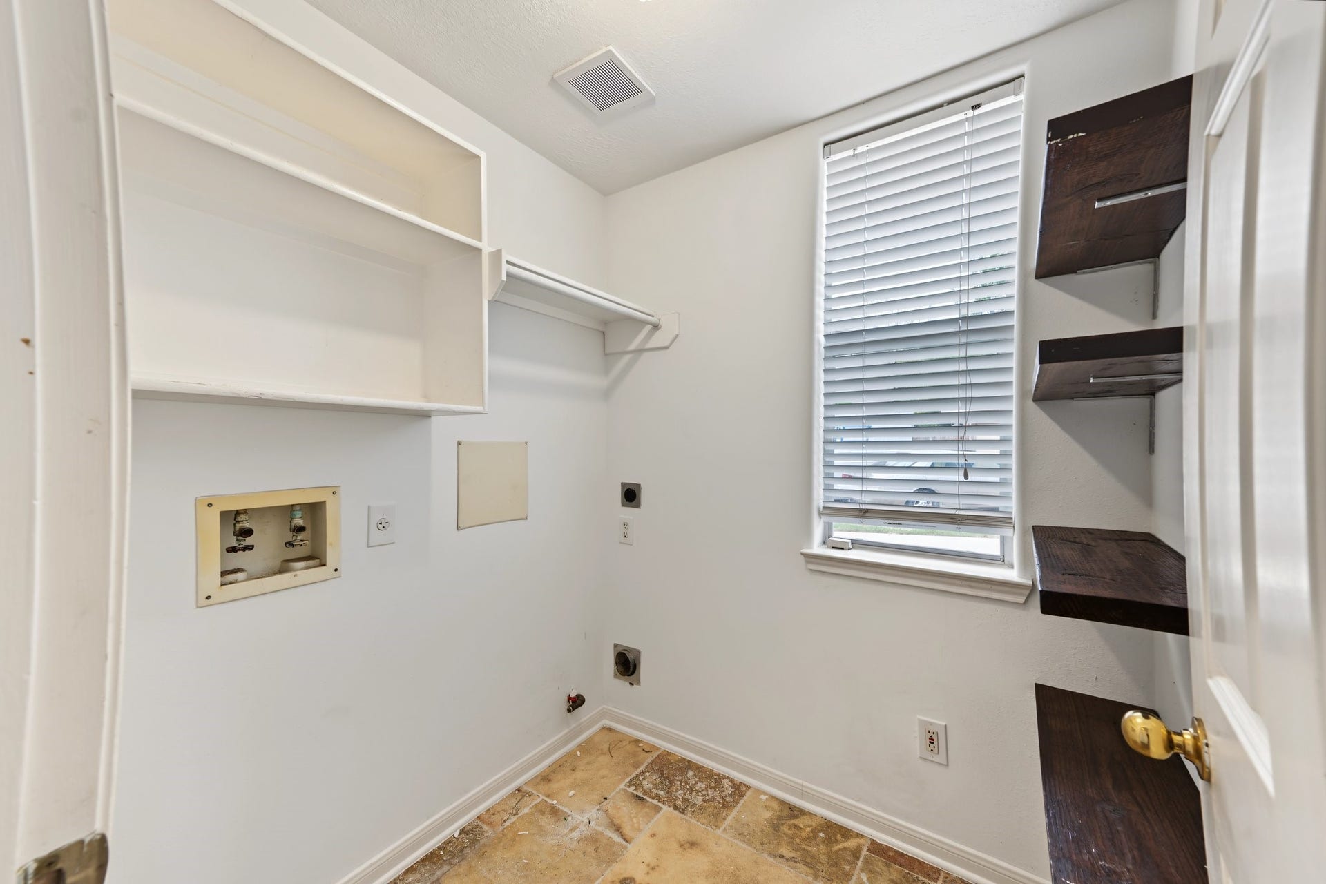 The laundry room features shelving, utility hookups, and natural light from a window with blinds. A hanging rack allows you to hang your clothes right after they come out of the dryer.