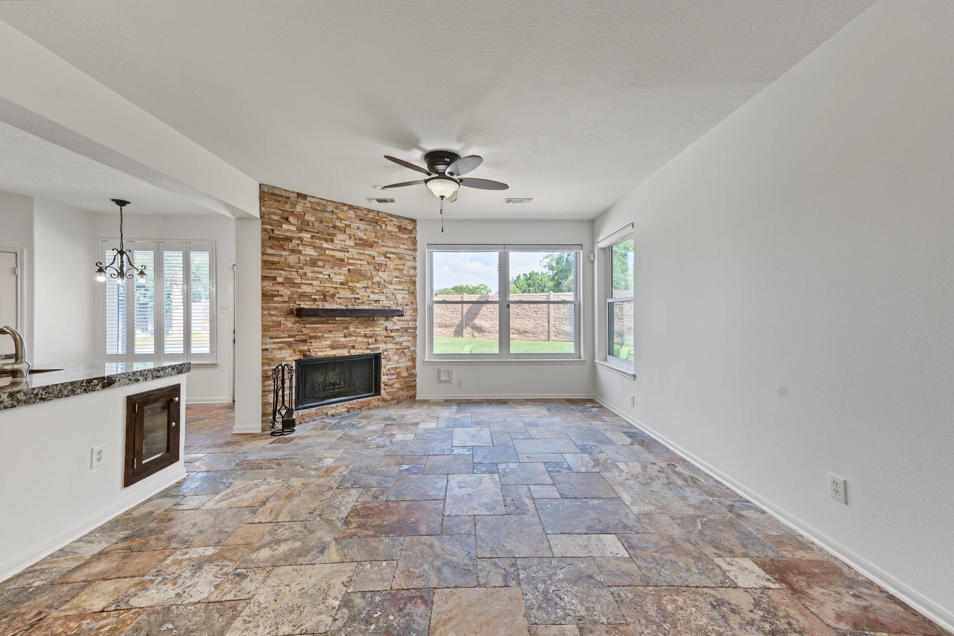 Wow! The living area has a stunning stone accent wall featuring a fireplace, complemented by large windows that flood the room with natural light with views of the large backyard and pool area.