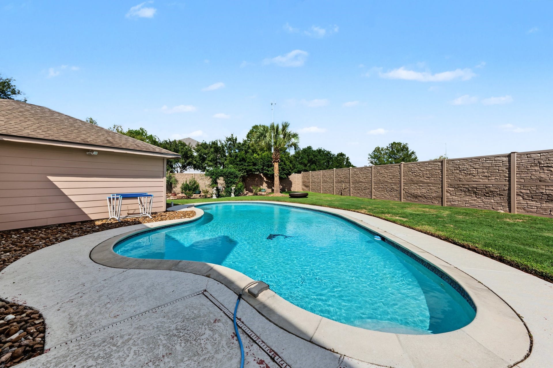 Enjoy a private oasis with this inviting backyard featuring a sparkling pool, surrounded by lush greenery and a privacy fence. Let's go!