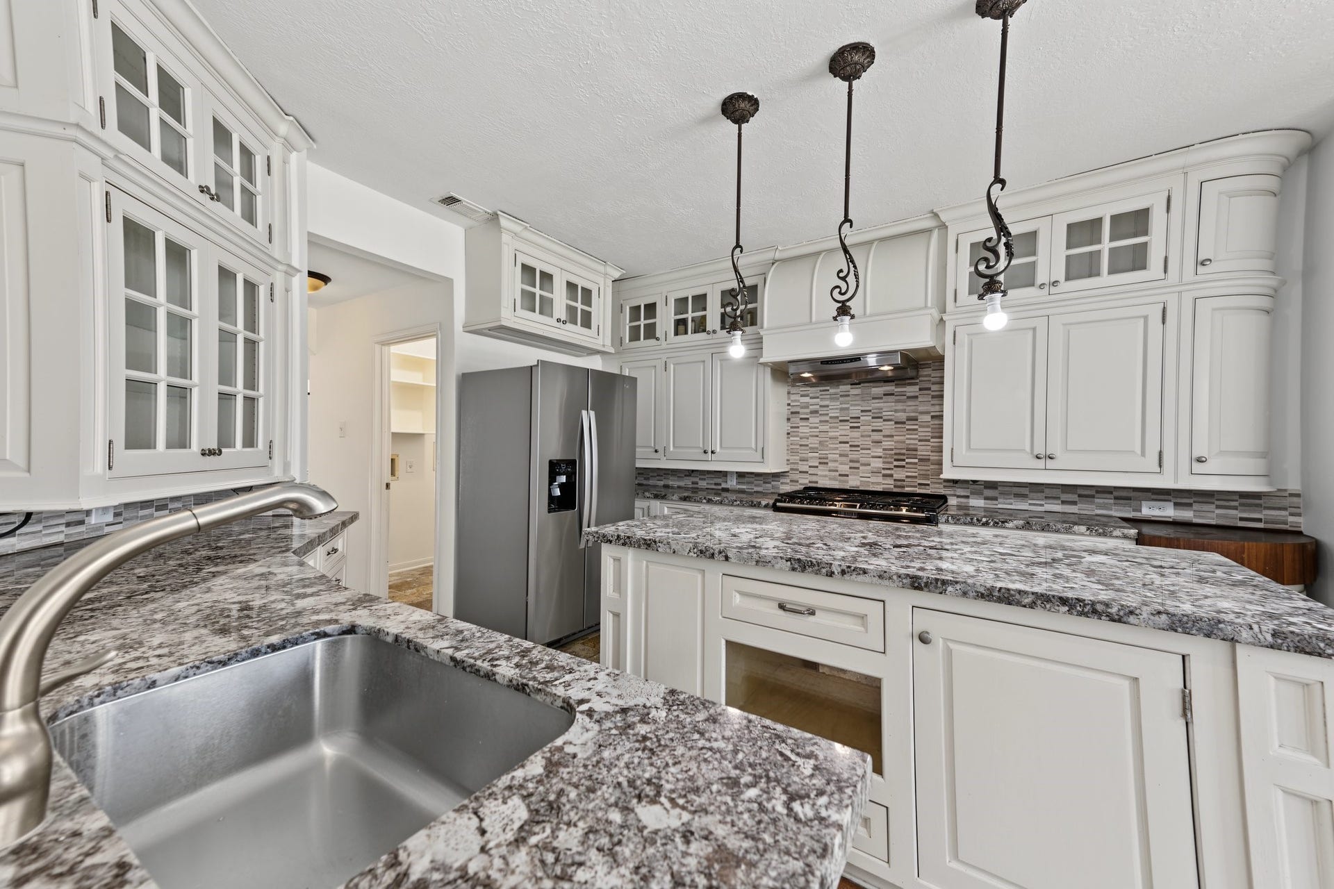 White cabinetry along with stainless fridge makes this a very appealing place to work, play and entertain.