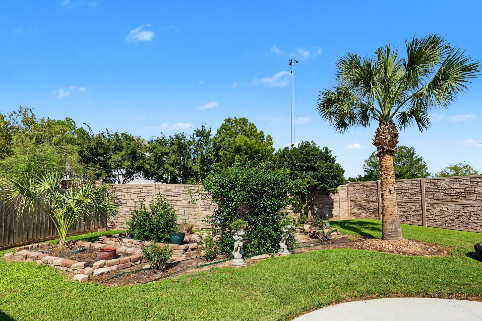Beautifully landscaped backyard with lush greenery, a charming stone-lined garden. Great for mediation or a little garden of your own.