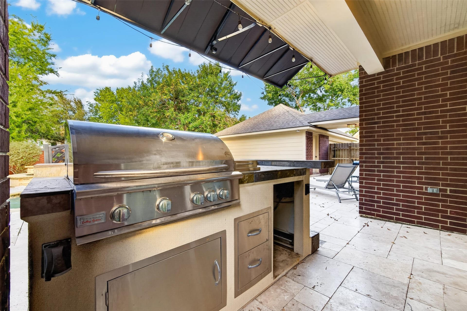7707 Stone Arbor Drive, Sugar Land, TX 77479 OUTDOOR COOKING JUST GOT MORE ENJOYABLE! This built-in gas grill makes preparing meals outdoors a pleasure, with generous countertop space for food preparation & serving, plus built-in storage below. The copper awning provides welcome shade over the cooking area, while the surrounding Travertine decking connects this outdoor kitchen to the poolside entertaining areas. Imagine grilling your favorite steaks while enjoying a beautiful Houston evening!