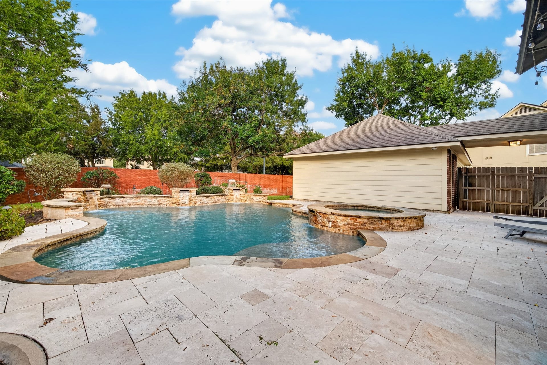 7707 Stone Arbor Drive, Sugar Land, TX 77479 YOUR OWN BACKYARD PARADISE! This gorgeous freeform pool features a PebbleTec finish, natural stone accents, cascading waterfalls & an elevated spa. Surrounded by expansive Travertine decking and mature landscaping, it's a wonderful setting for cooling off on a warm Texas afternoon or simply relaxing beside the water.