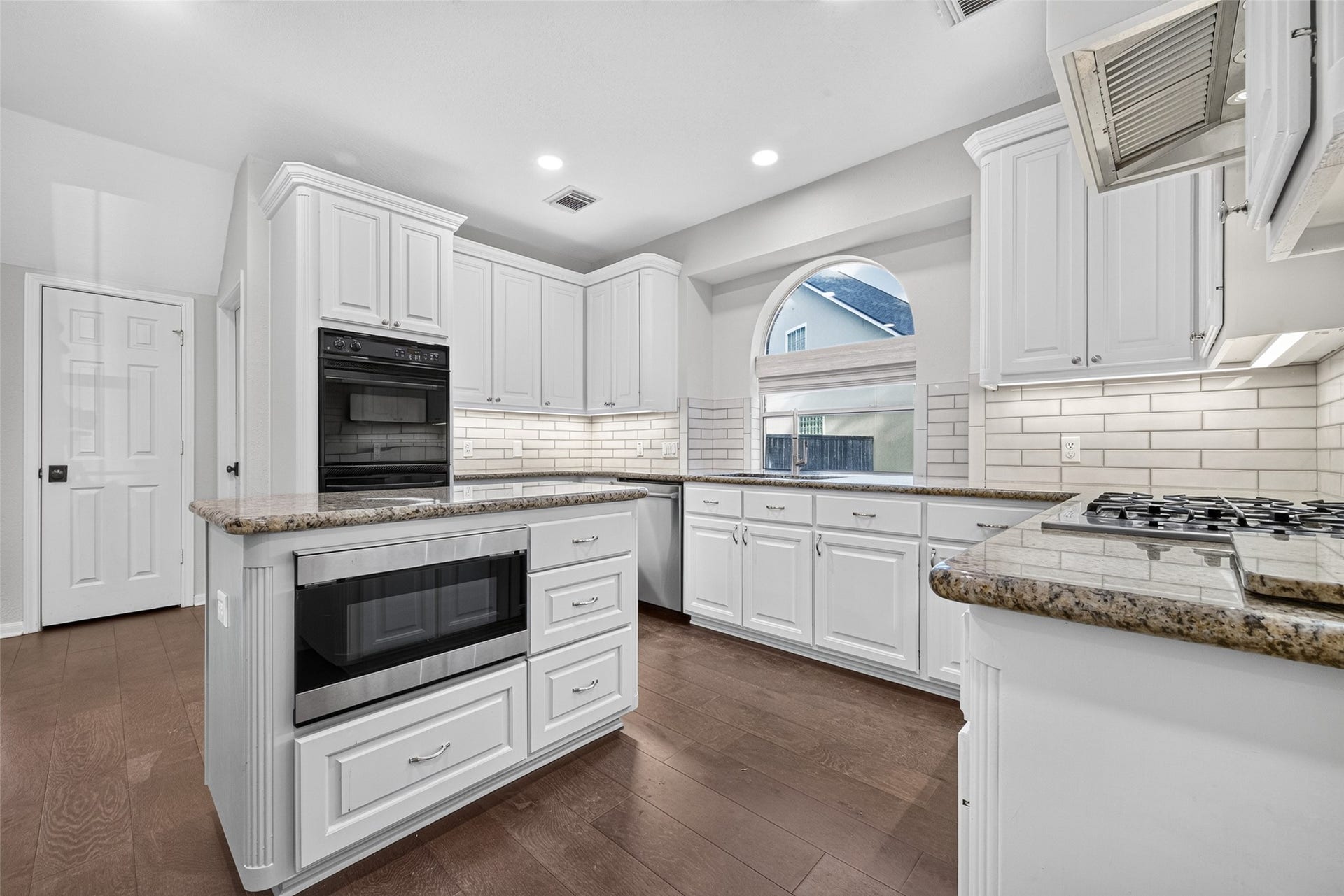 7707 Stone Arbor Drive, Sugar Land, TX 77479 A KITCHEN THAT MAKES GOOD USE OF ITS SPACE! From this angle, you can appreciate how the island, double ovens, gas cooktop & sink are arranged for everyday convenience. The white cabinetry provides generous storage, while the granite countertops offer multiple preparation areas. Recessed lighting, undercabinet lighting & wood flooring complete the space.