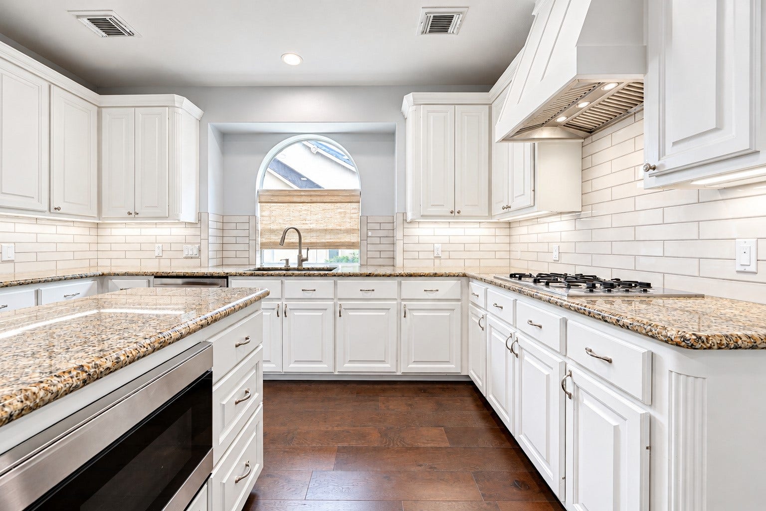 7707 Stone Arbor Drive, Sugar Land, TX 77479 FOR THOSE WHO LOVE TO COOK! The gas cooktop sits beneath a decorative vent hood, surrounded by granite countertops & a crisp white subway tile backsplash. Gas cooking offers responsive temperature control, allowing you to move quickly from a gentle simmer to a rolling boil or adjust the heat while preparing your favorite recipes. With the center island nearby for chopping ingredients, organizing spices or setting out serving dishes, this thoughtfully arranged kitchen makes meal preparation enjoyable.
