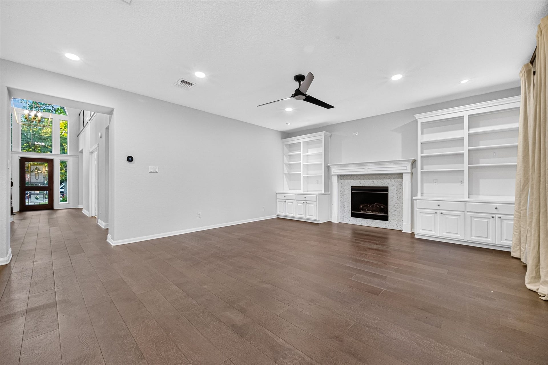 7707 Stone Arbor Drive, Sugar Land, TX 77479 A FAMILY ROOM DESIGNED FOR COMFORT! Spacious & inviting, this Family Room features beautiful wood flooring, recessed lighting, a contemporary ceiling fan & a gas-log fireplace framed by white built-in cabinetry & display shelves. The generous proportions offer plenty of flexibility for arranging furniture, whether you prefer a large sectional for movie nights or separate seating areas for conversation. There's room to relax, unwind & make yourself at home.